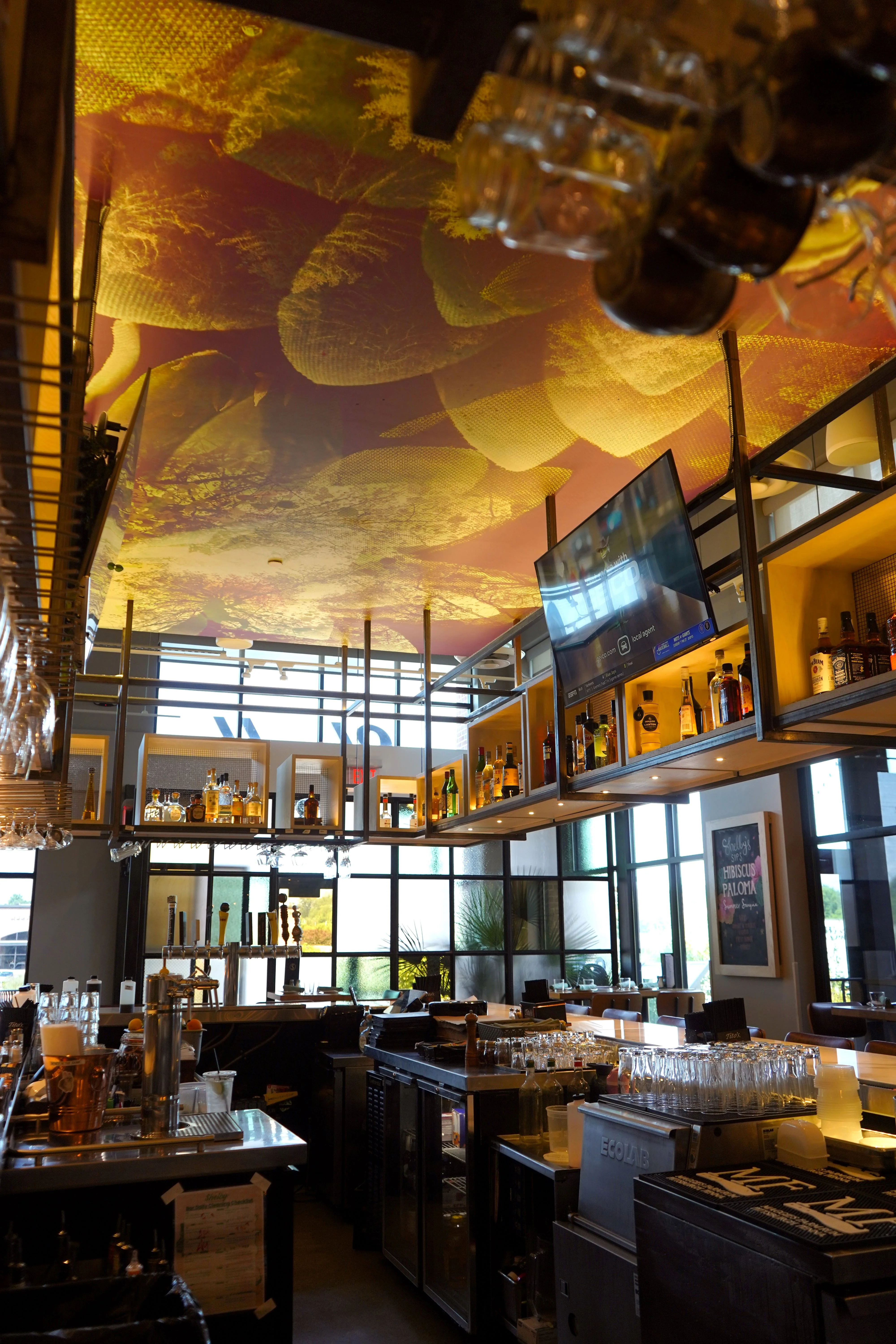 Modern bar interior with artistic ceiling and well-stocked shelves