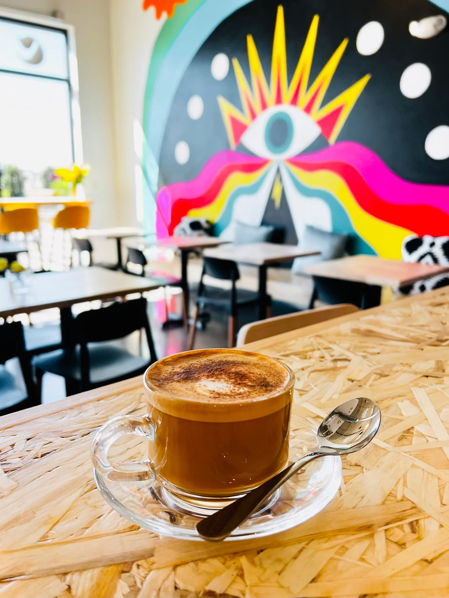 Artistic coffee cup on a wooden table in a vibrant café interior