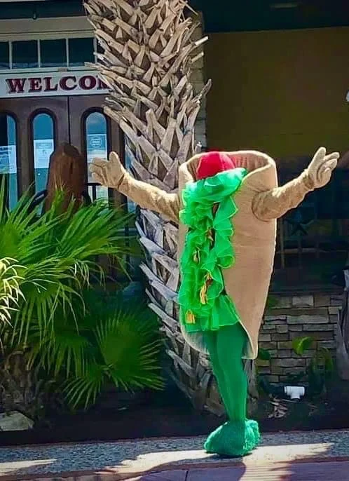 Costumed taco character welcoming guests outside a restaurant
