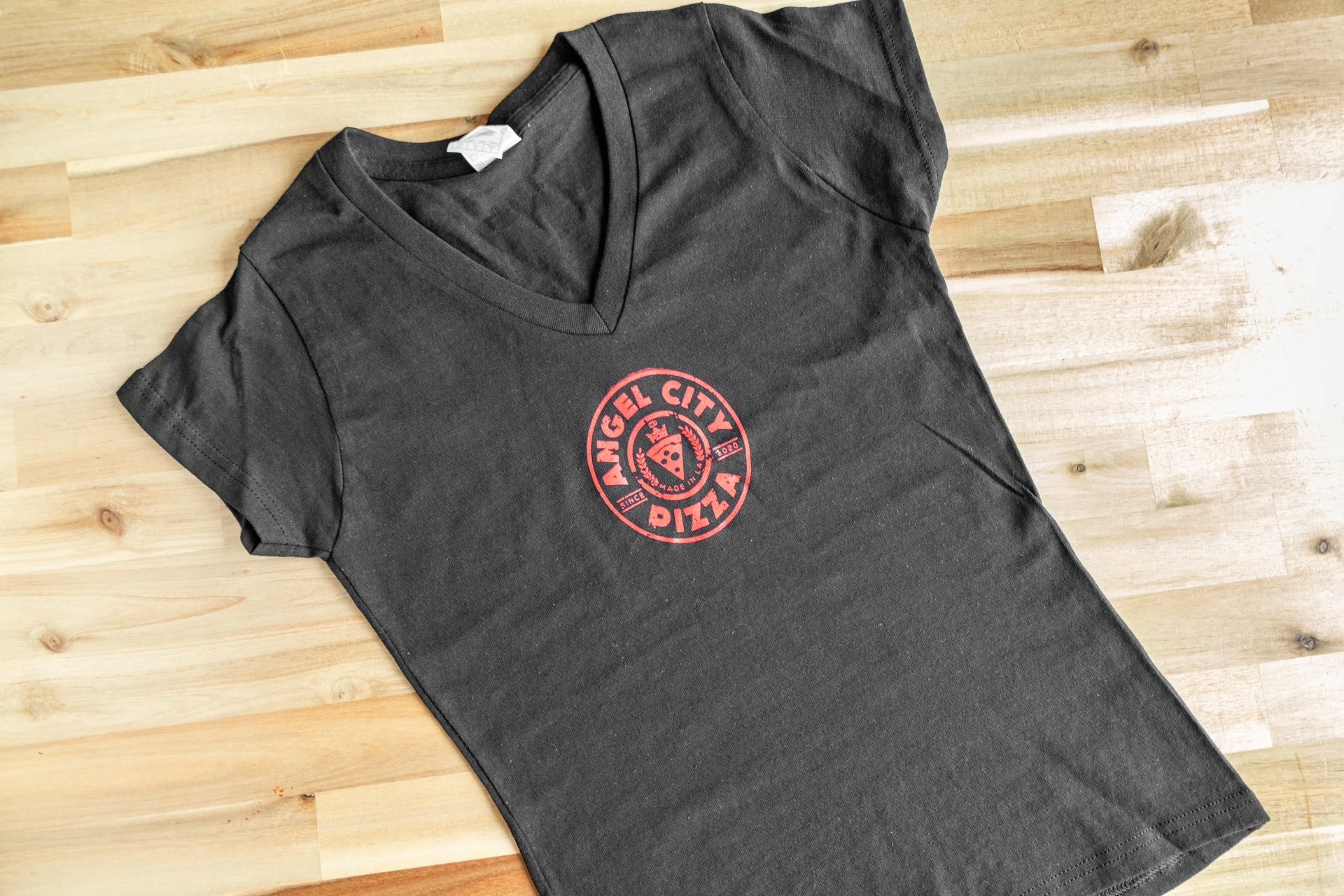 Angel City Pizza branded v-neck t-shirt on wooden surface