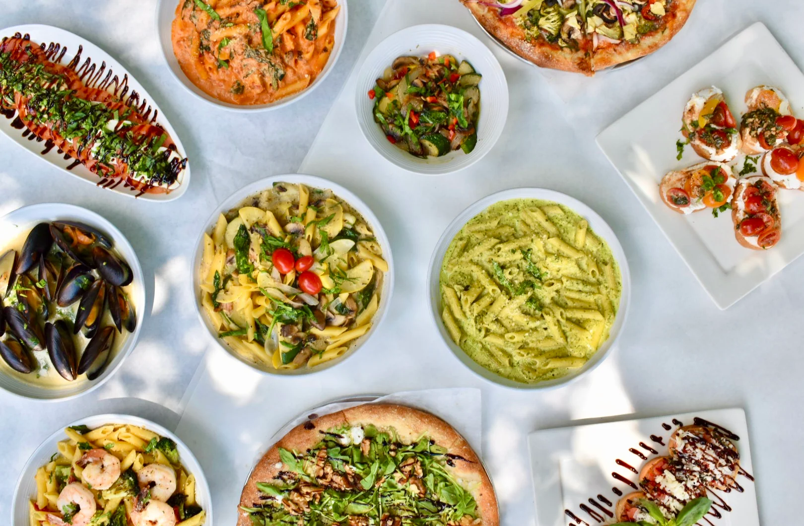 Italian pasta dishes and pizza on a dining table