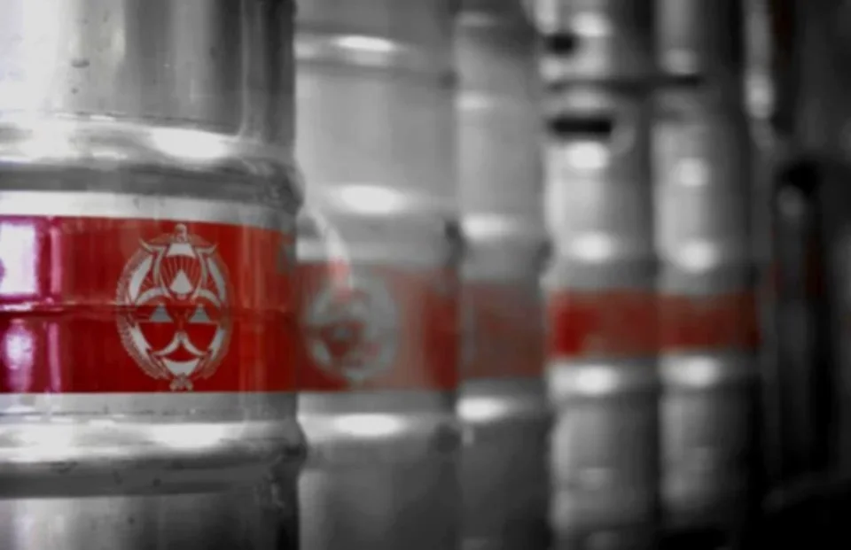 Close-up of beer kegs with red branding in a brewery
