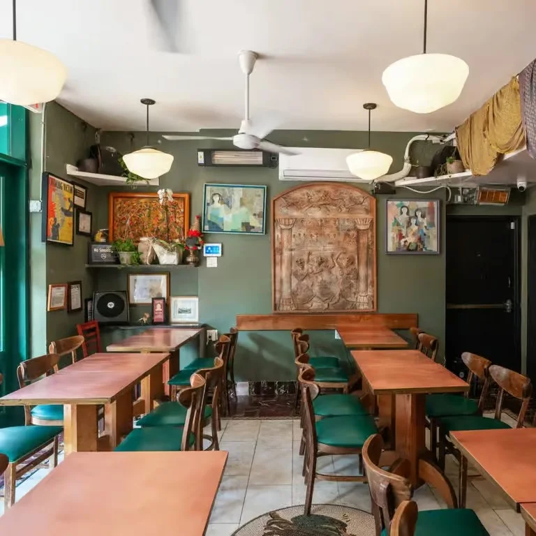 Exterior view of Moustache restaurant with green doors and outdoor seating.