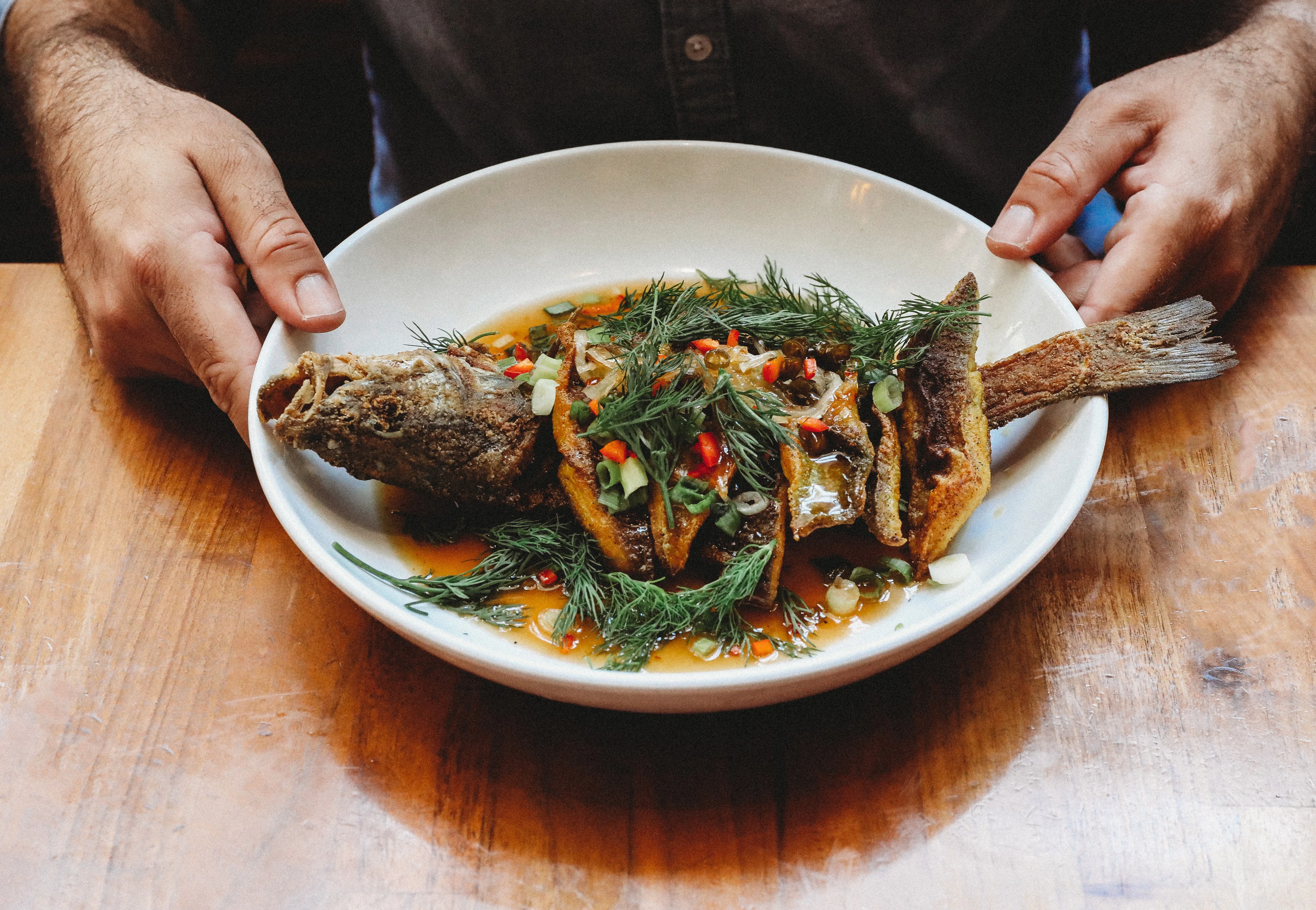 Crispy whole fish with herbs in a flavorful sauce
