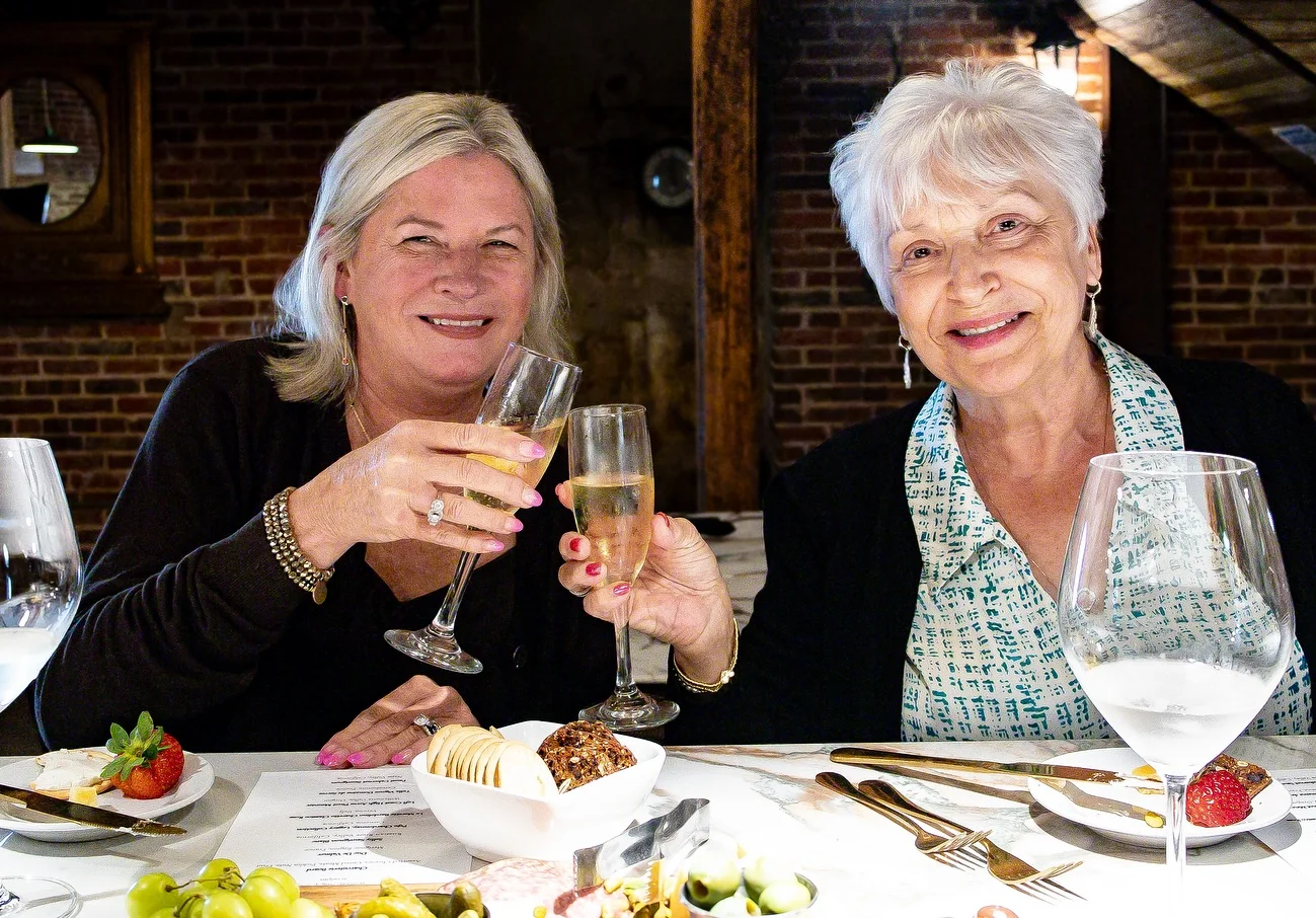 Two women toasting with champagne glasses in a cozy restaurant setting