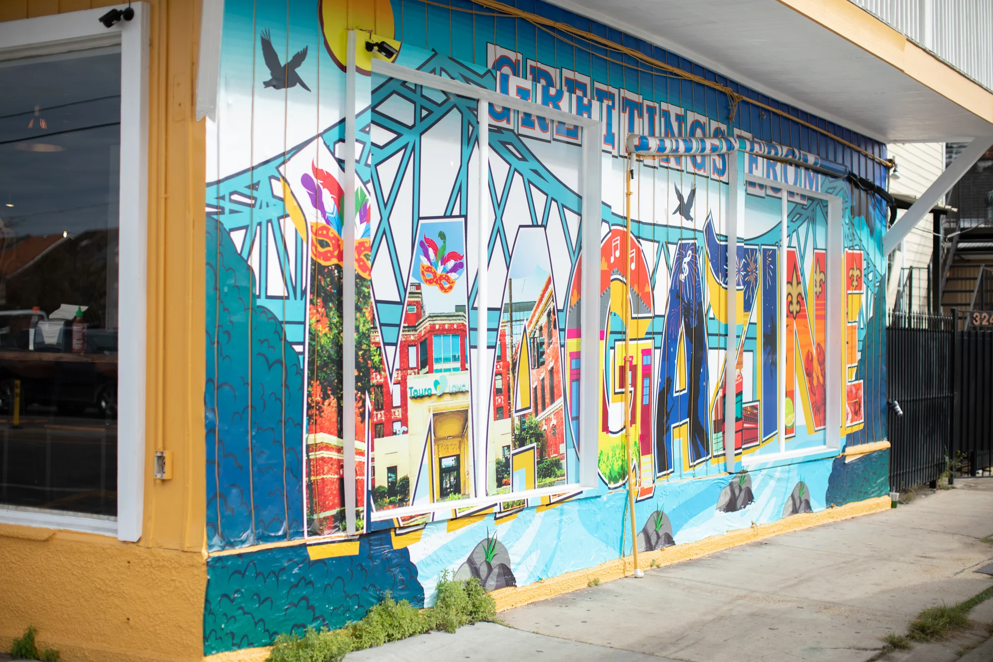 Colorful mural on a restaurant wall featuring 'Greetings from Magazine'.
