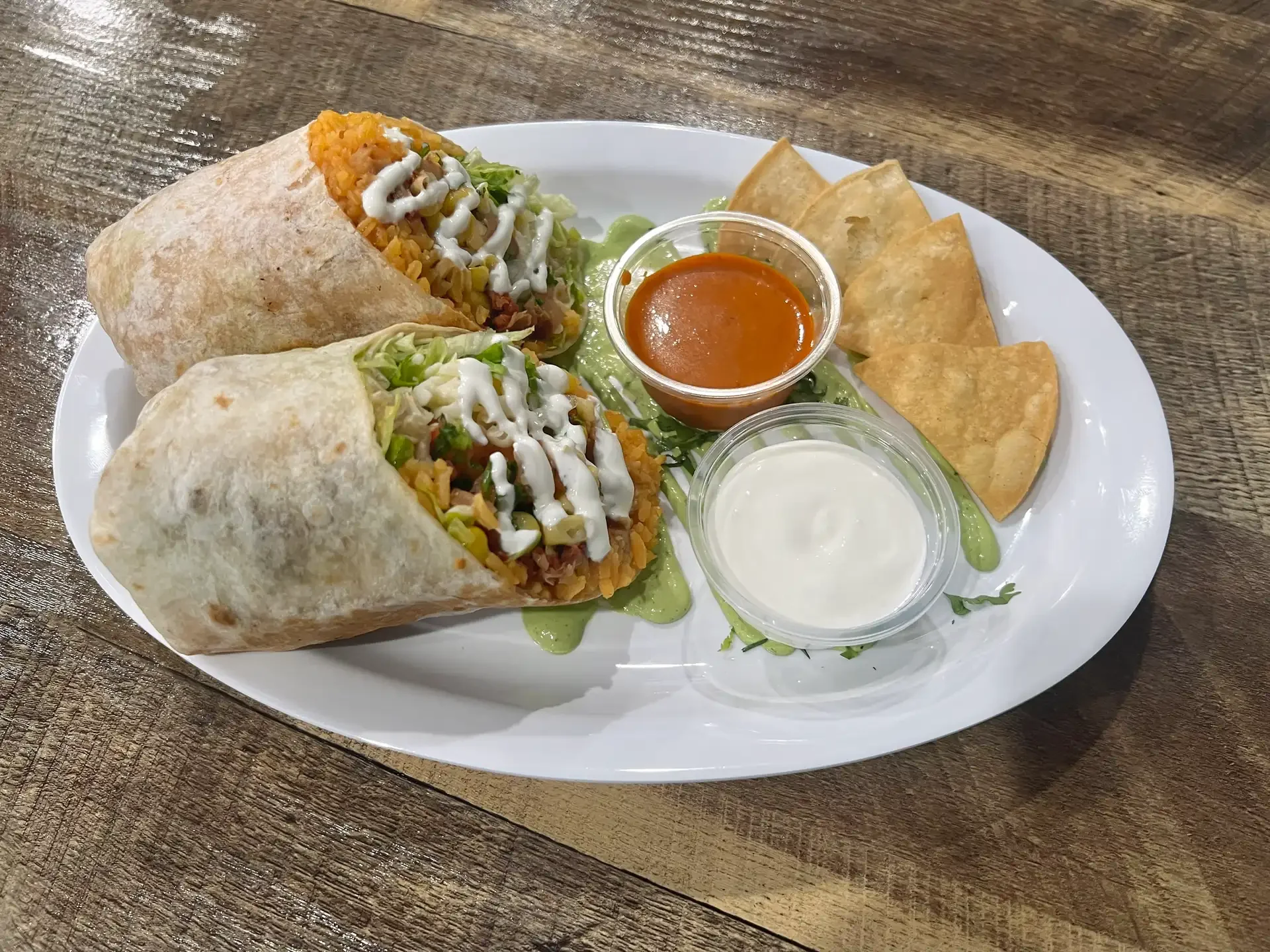 A generously stuffed burrito from El Ranchito Poblano in Brooklyn, cut in half and served with sour cream, salsa, and fried tortilla chips.