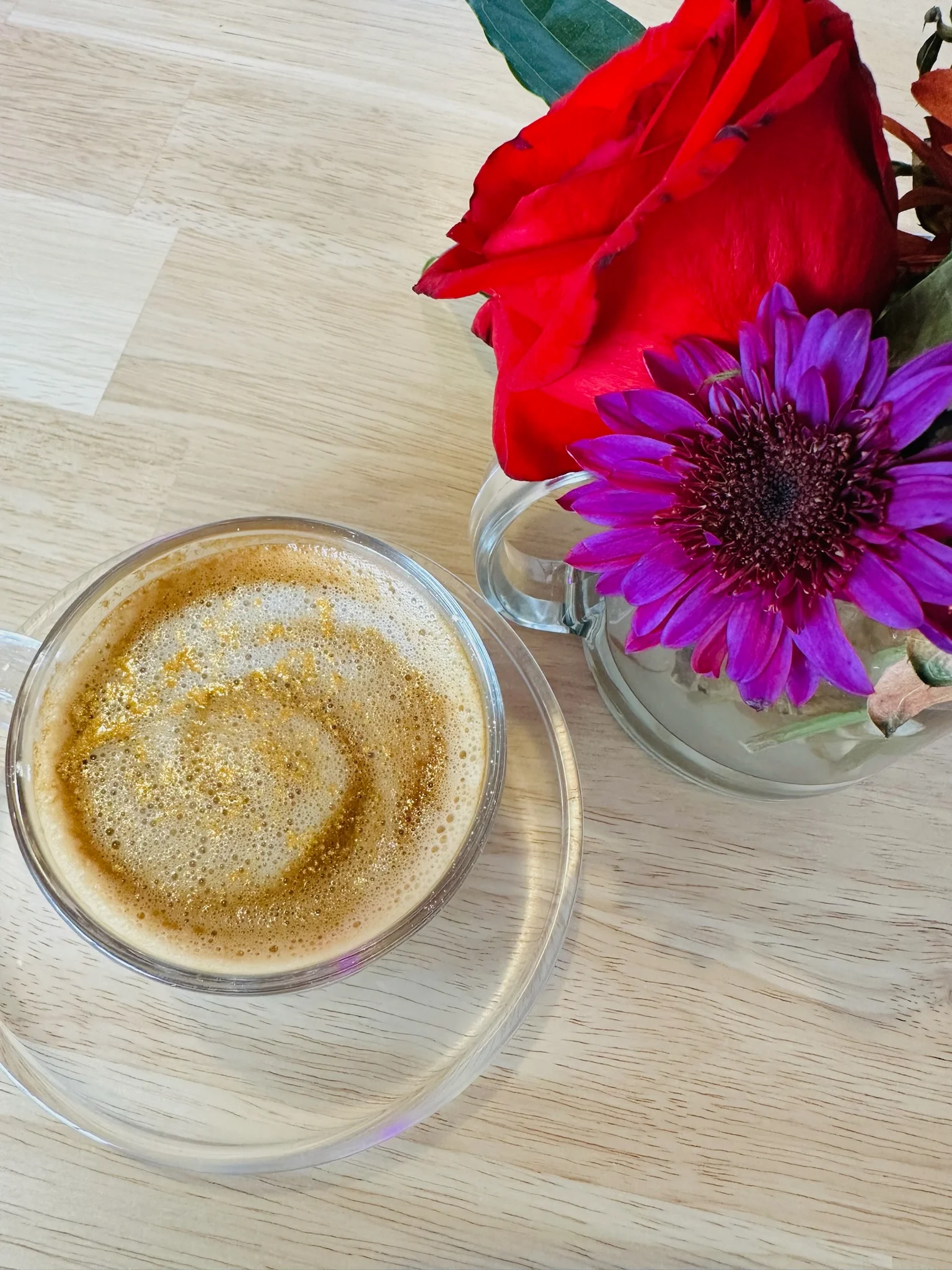 Artisan coffee topped with golden foam and surrounded by vibrant flowers