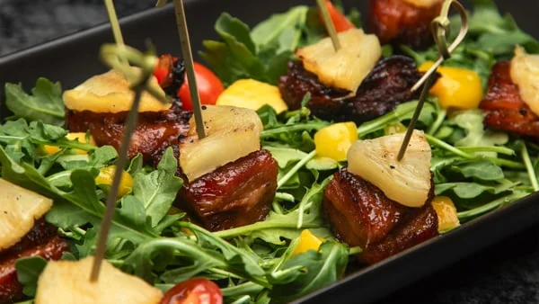 Hawaiian-style pork skewers on arugula salad