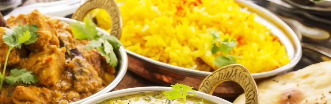 Indian thali with chicken curry, shrimp dish, saffron rice, and naan