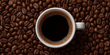 Cup of rich black coffee surrounded by roasted coffee beans