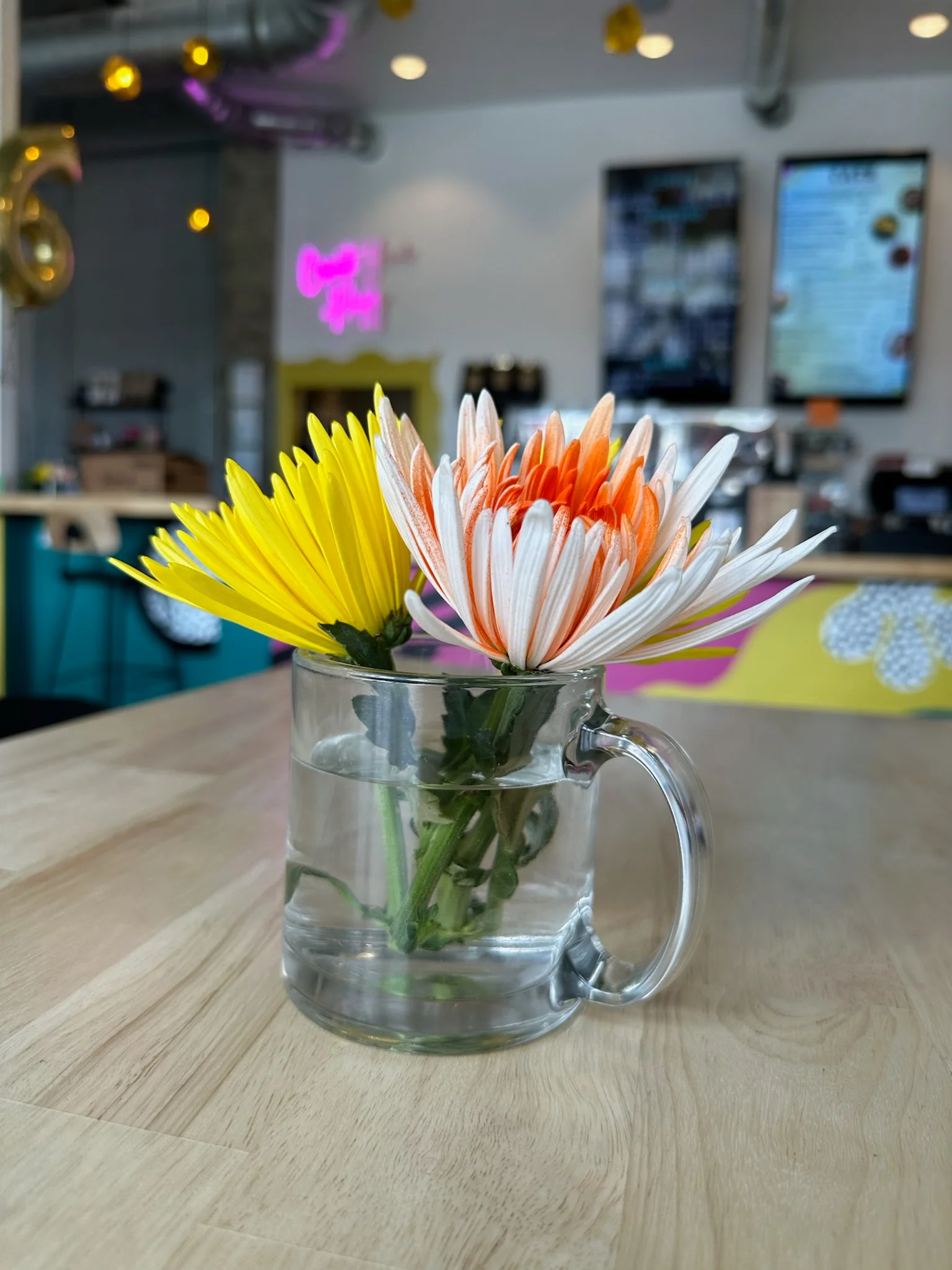Colorful flowers in a glass mug on a wooden table