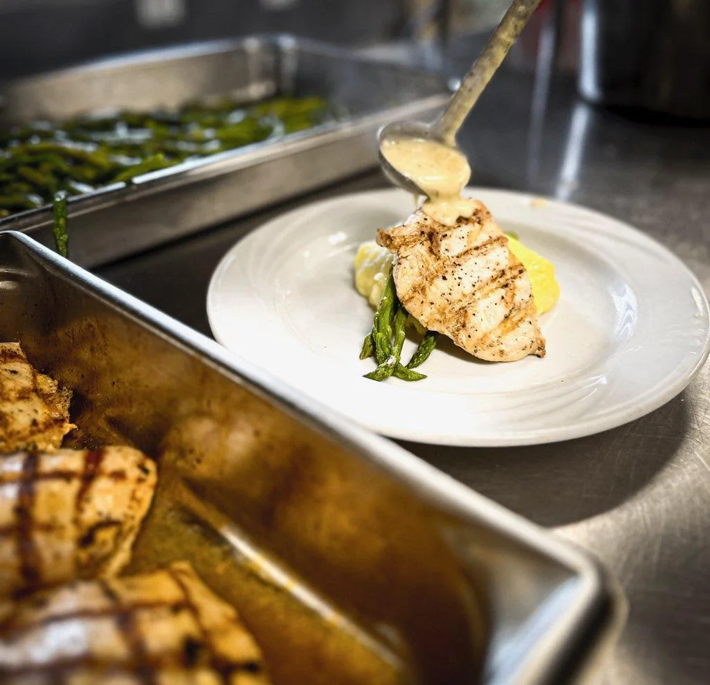 - Grilled chicken being plated for Brunch House catering service
