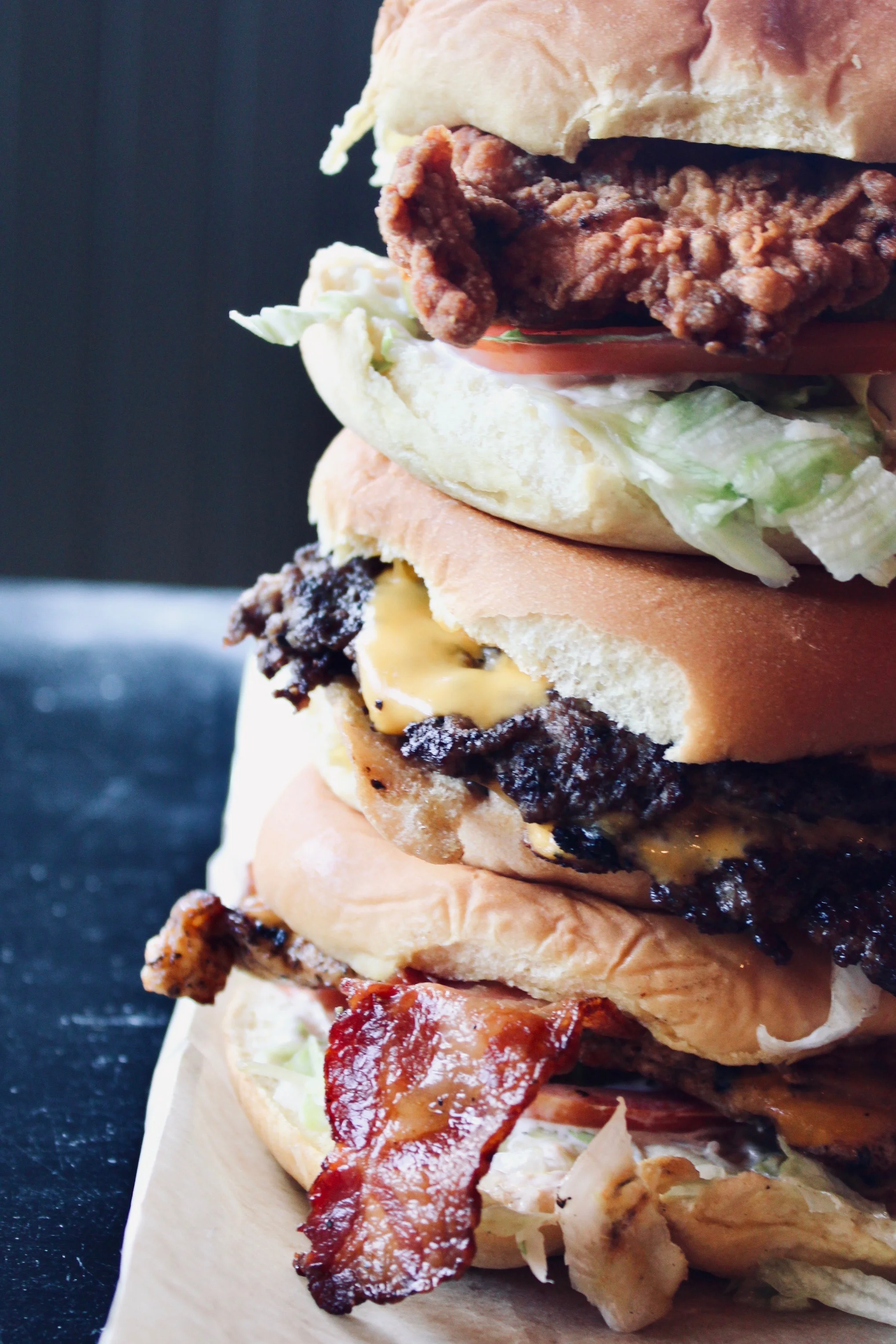 Stacked gourmet burgers with fried chicken and bacon