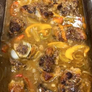 Tender oxtails cooked in a rich brown gravy with peppers and onions.