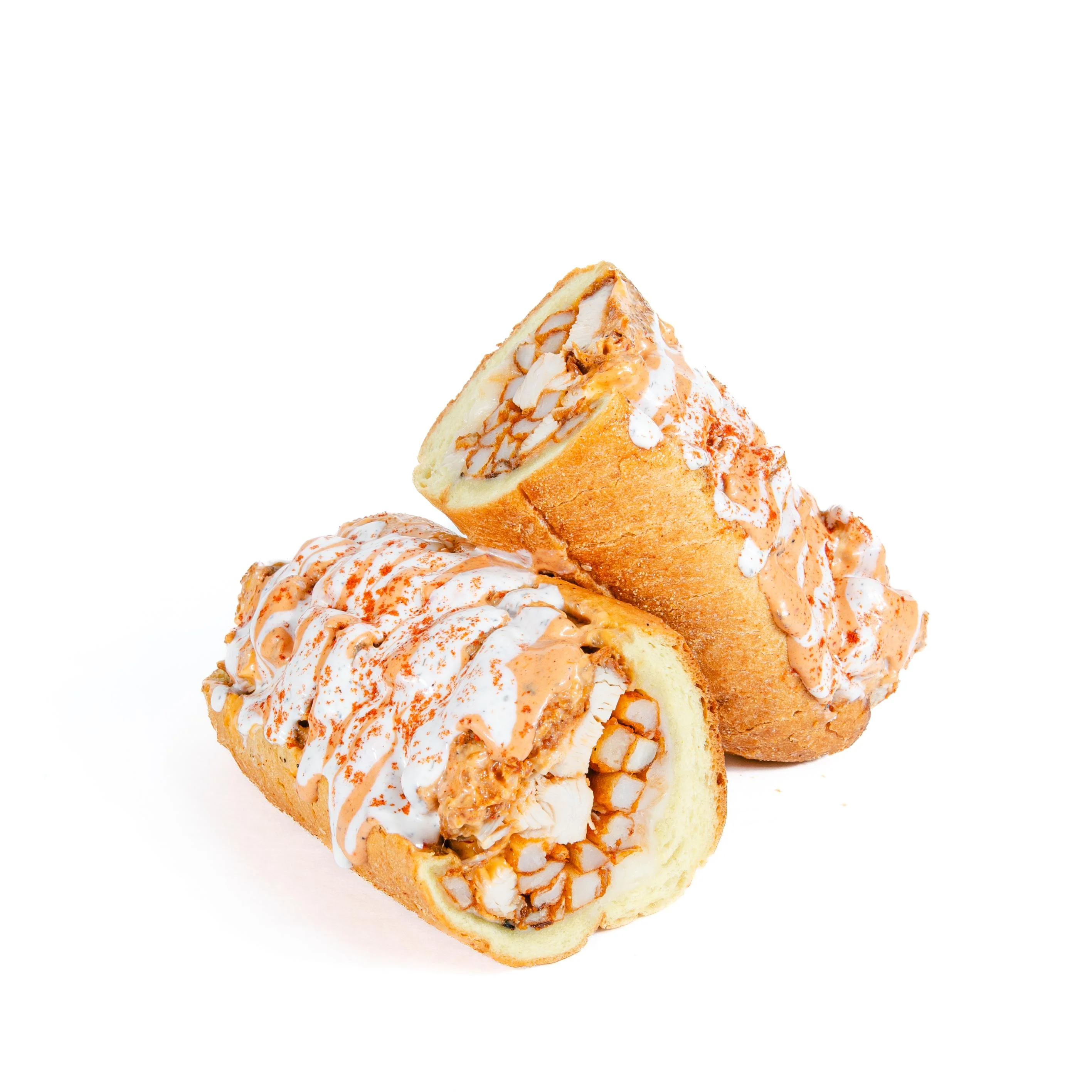 Two portions of a sweet dessert item, drizzled with icing and spices, displaying a soft interior.