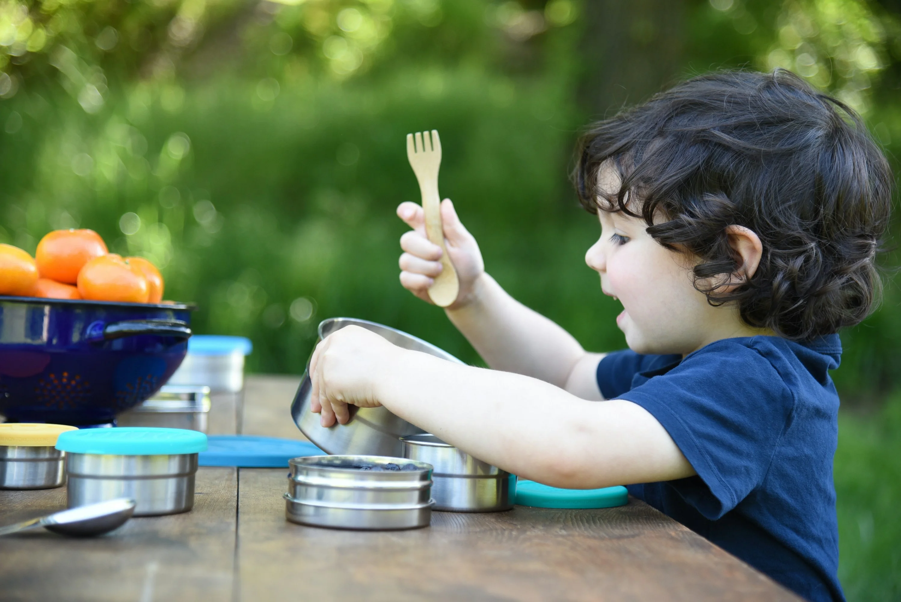 A kid seated at a table with a fork in hand.