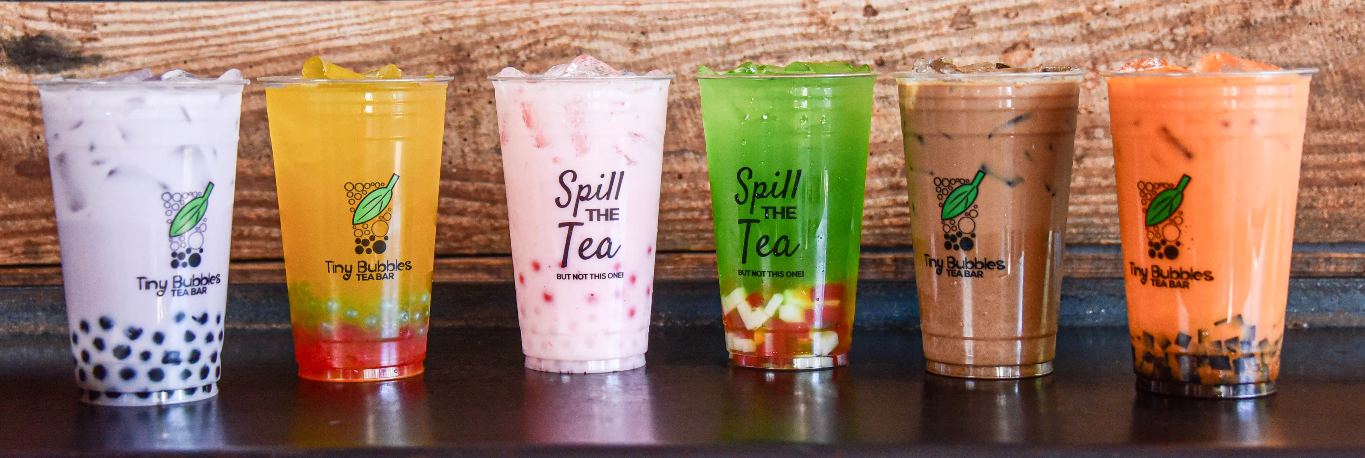 Colorful bubble tea drinks in clear cups on a rustic wooden table