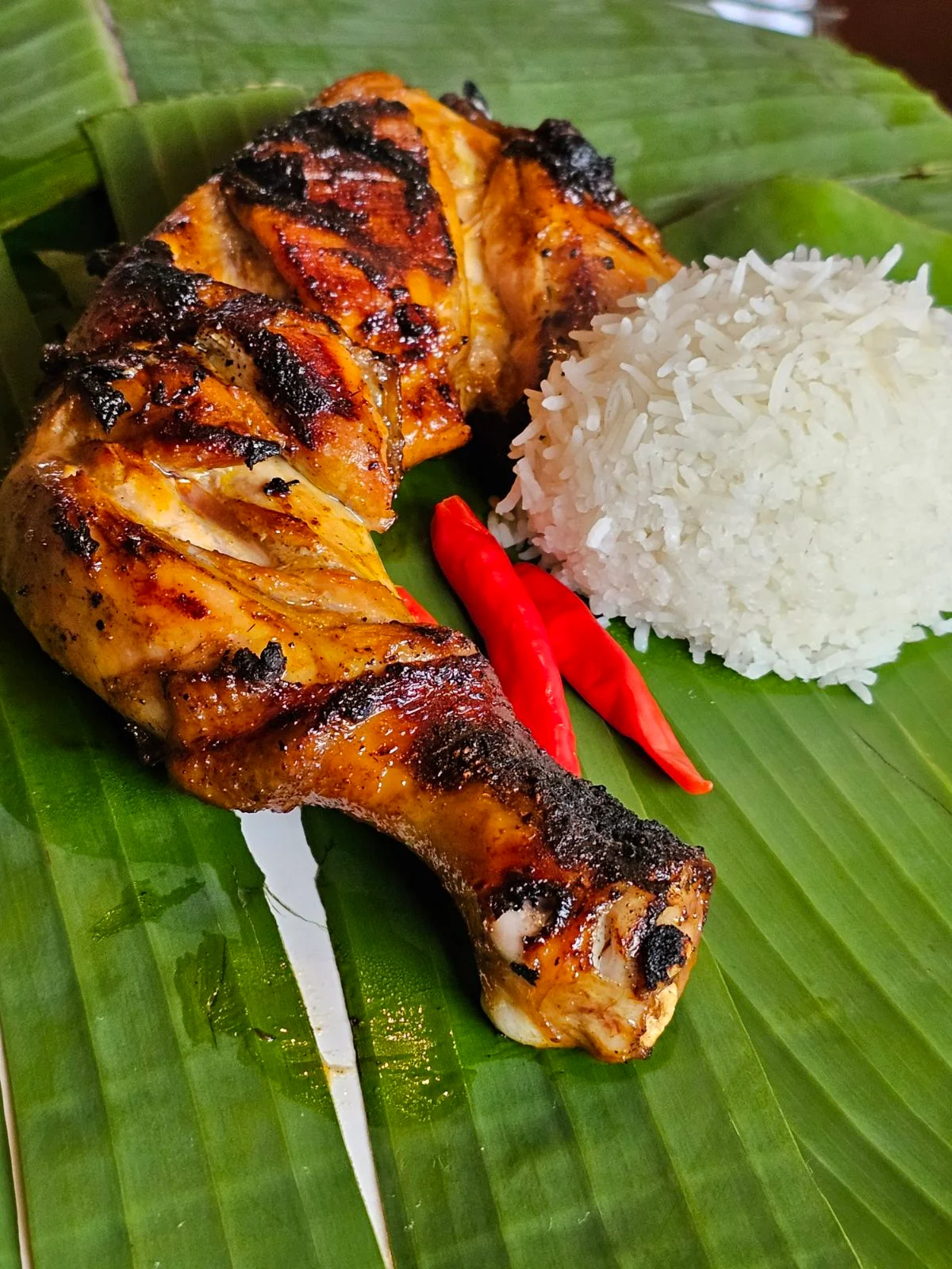 Grilled Indonesian ayam bakar with rice and chili peppers