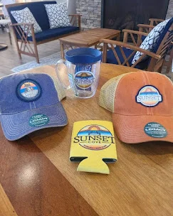Collection of branded merchandise including hats and a mug on a wooden table