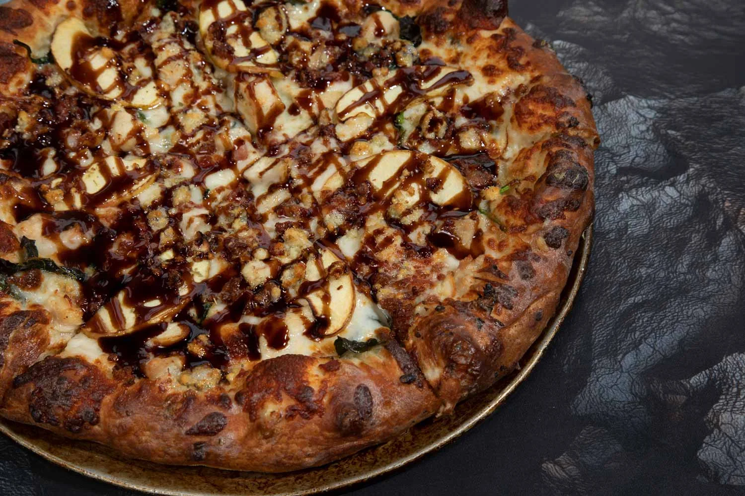 Gourmet dessert pizza drizzled with chocolate sauce and topped with apple slices