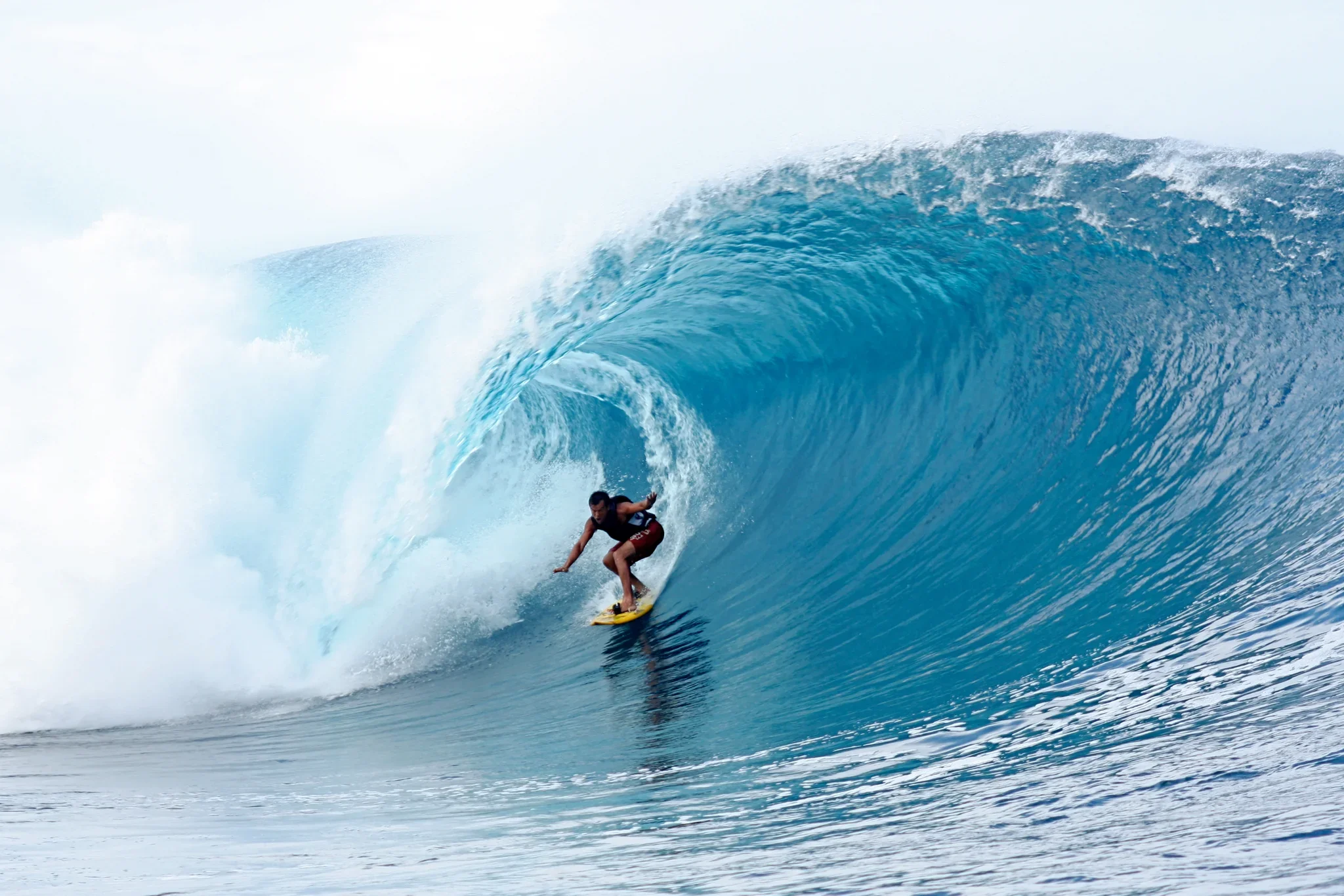 Surfer riding a massive blue wave