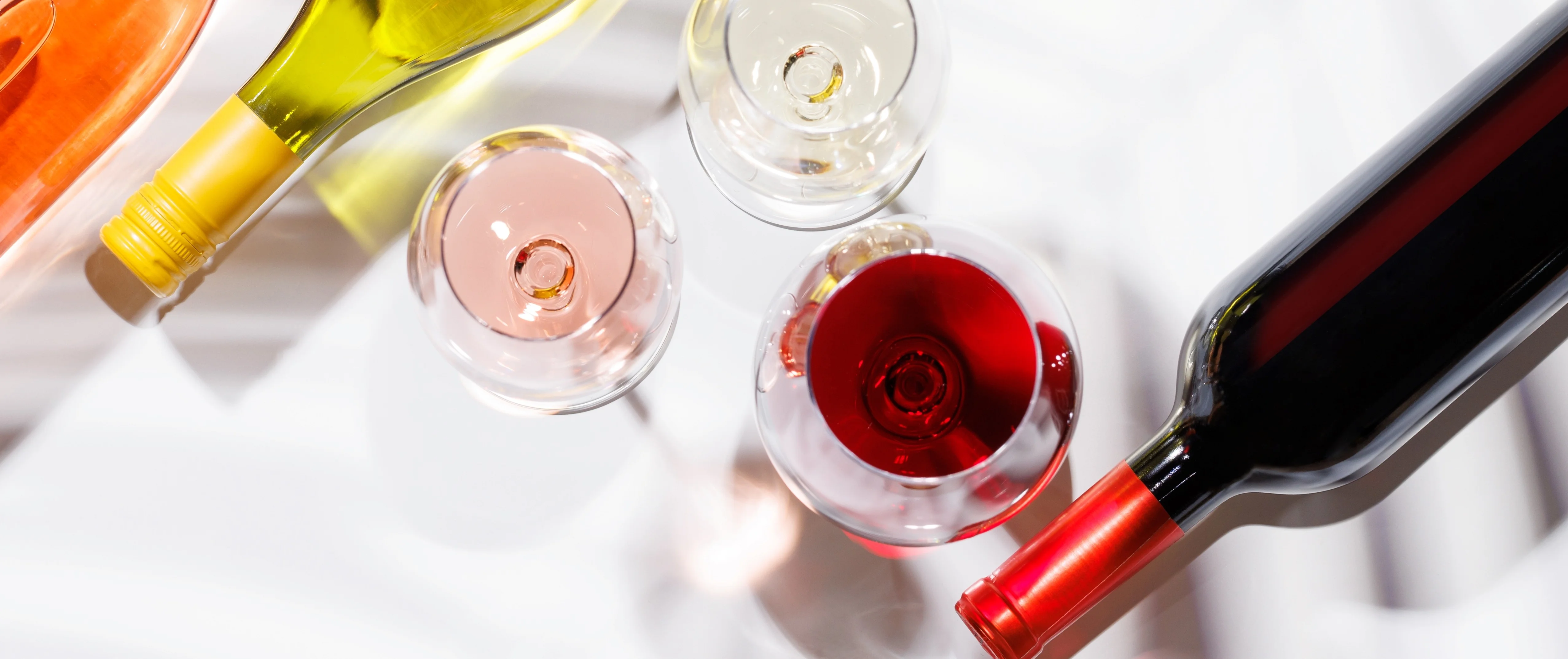 Assorted wine bottles and glasses on a light background