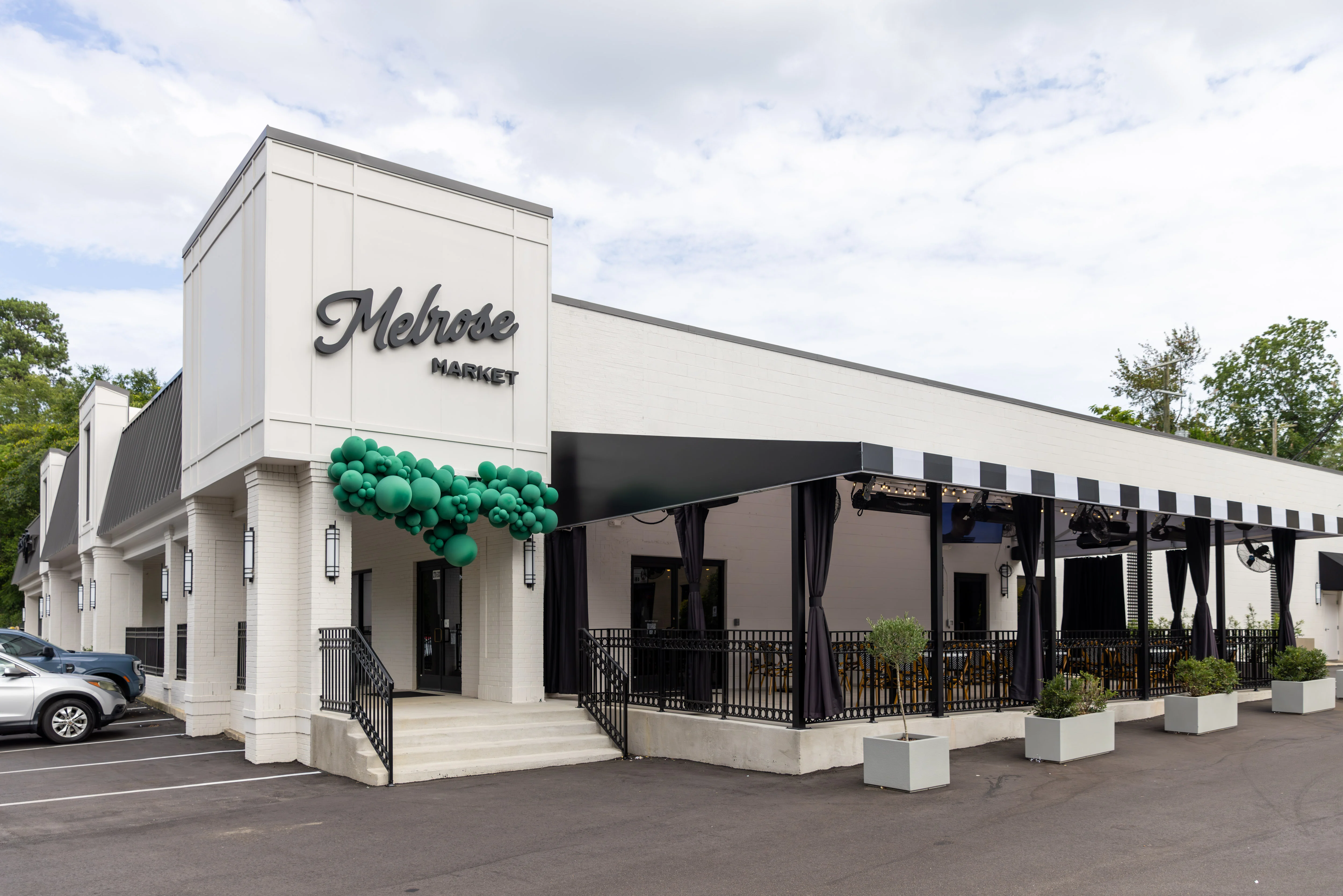 Modern restaurant exterior with covered patio and green balloon installation