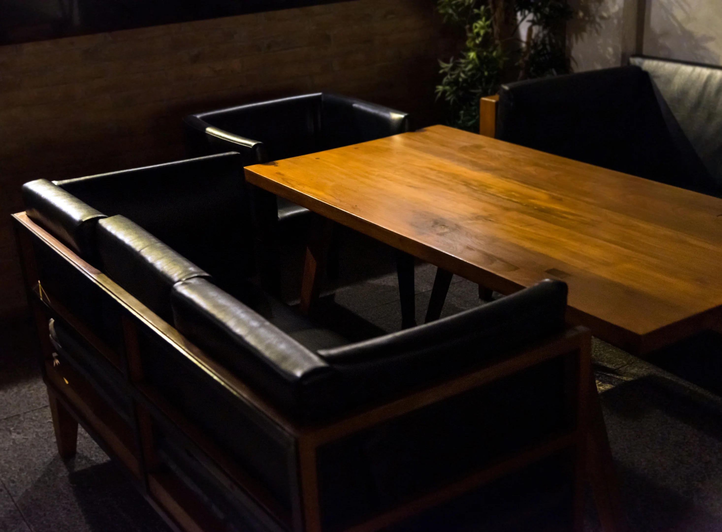 Cozy seating area with wooden table and black leather chairs.