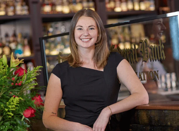 Bartender smiling at a stylish bar with a variety of spirits