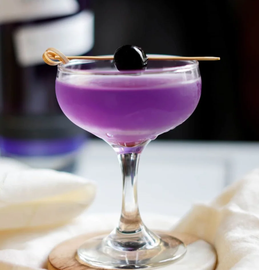 Vibrant purple cocktail garnished with a cherry