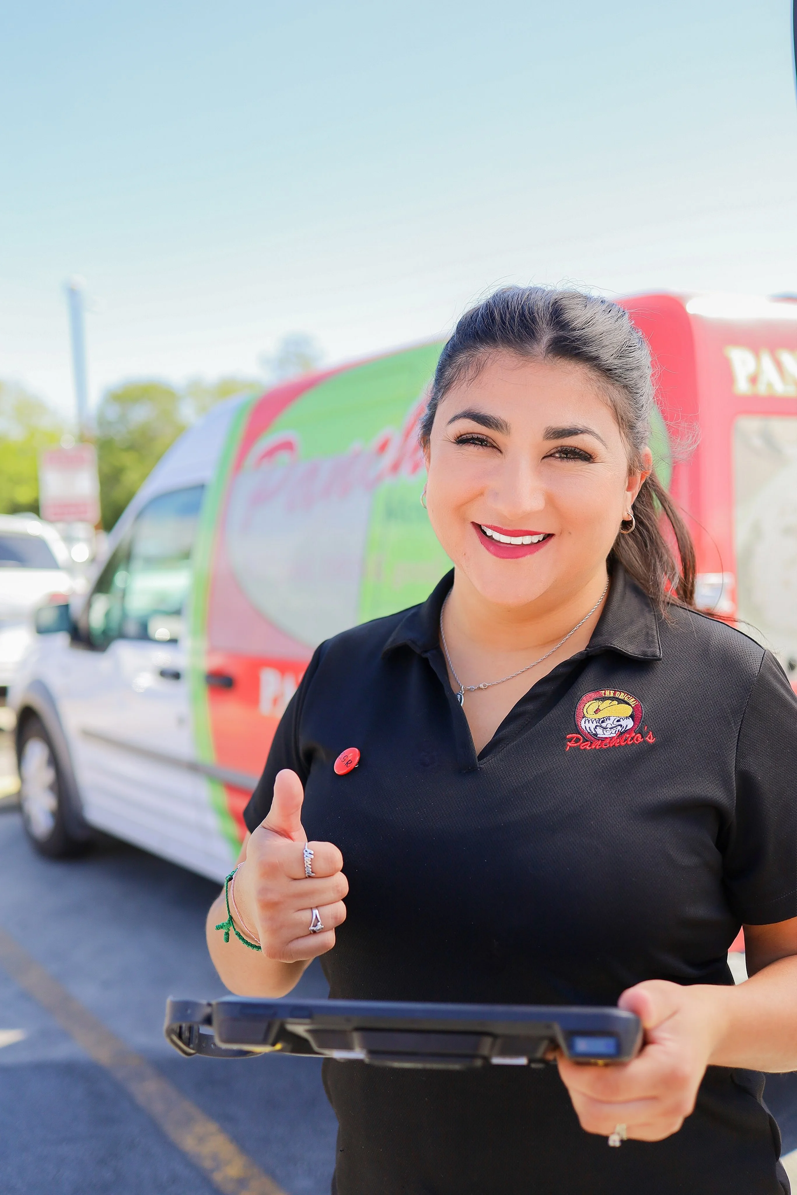 Friendly restaurant staff member with tablet and delivery van