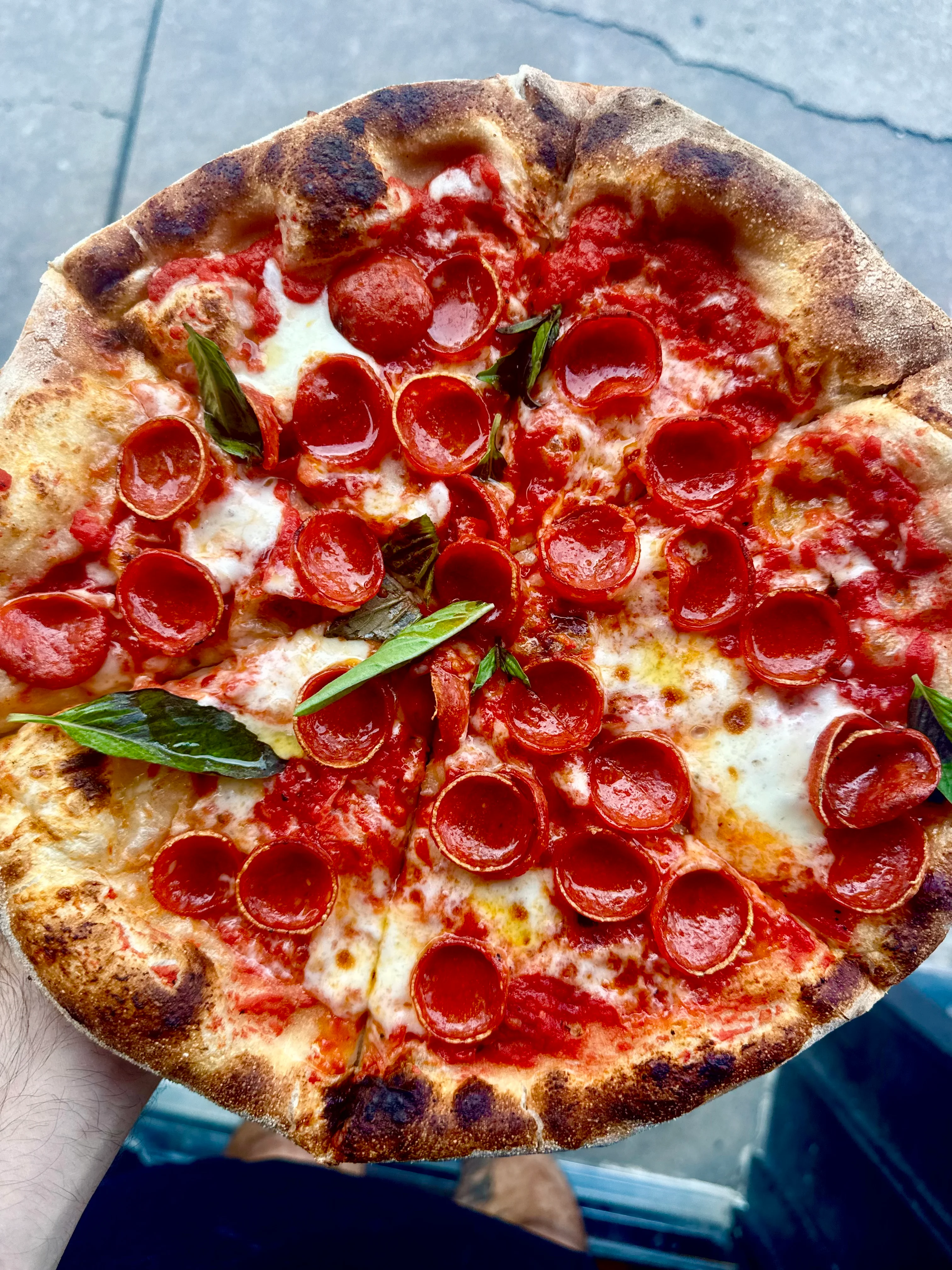 Close-up of Italian pepperoni pizza with basil and blistered crust