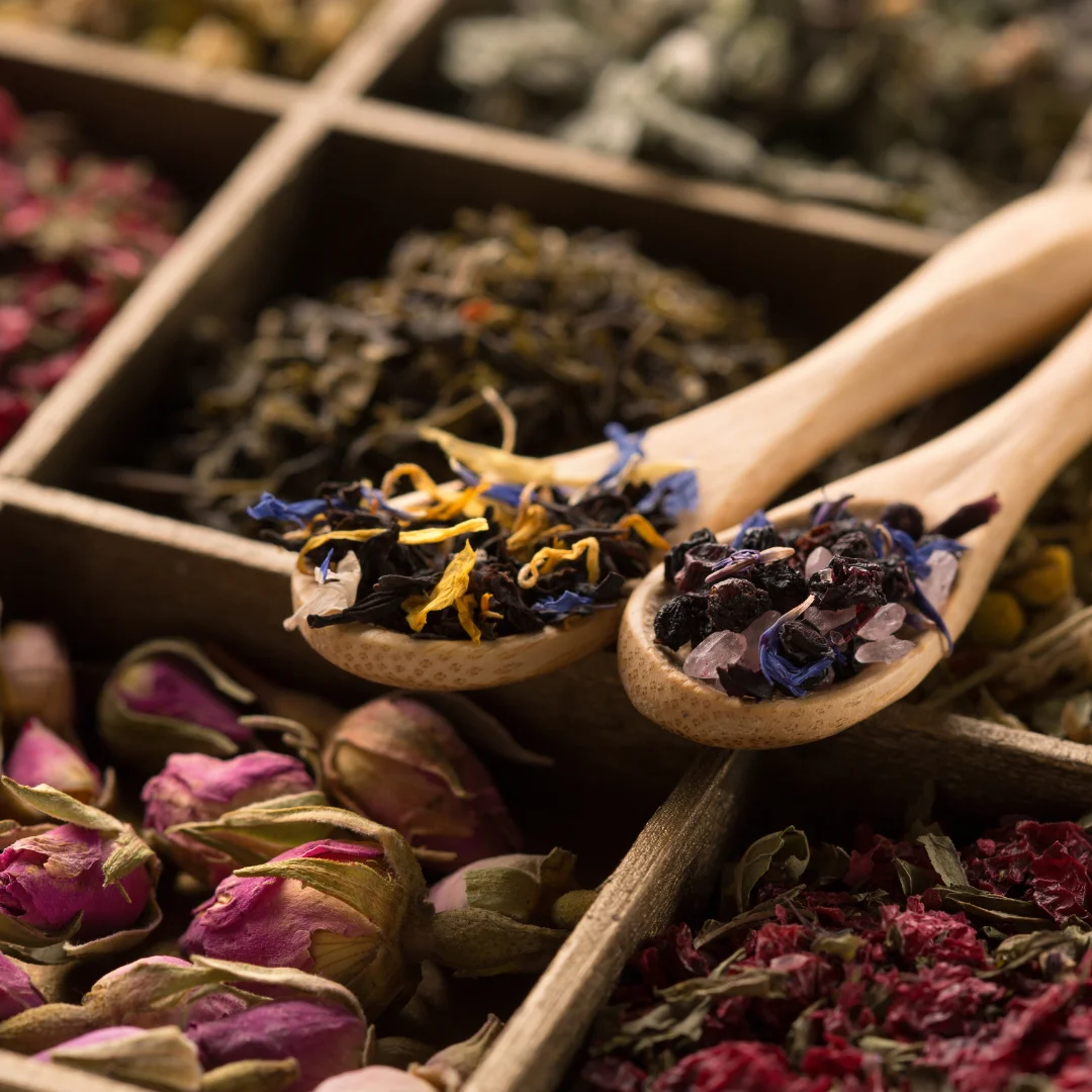 Colorful assortment of dried herbs and flowers in wooden spoons