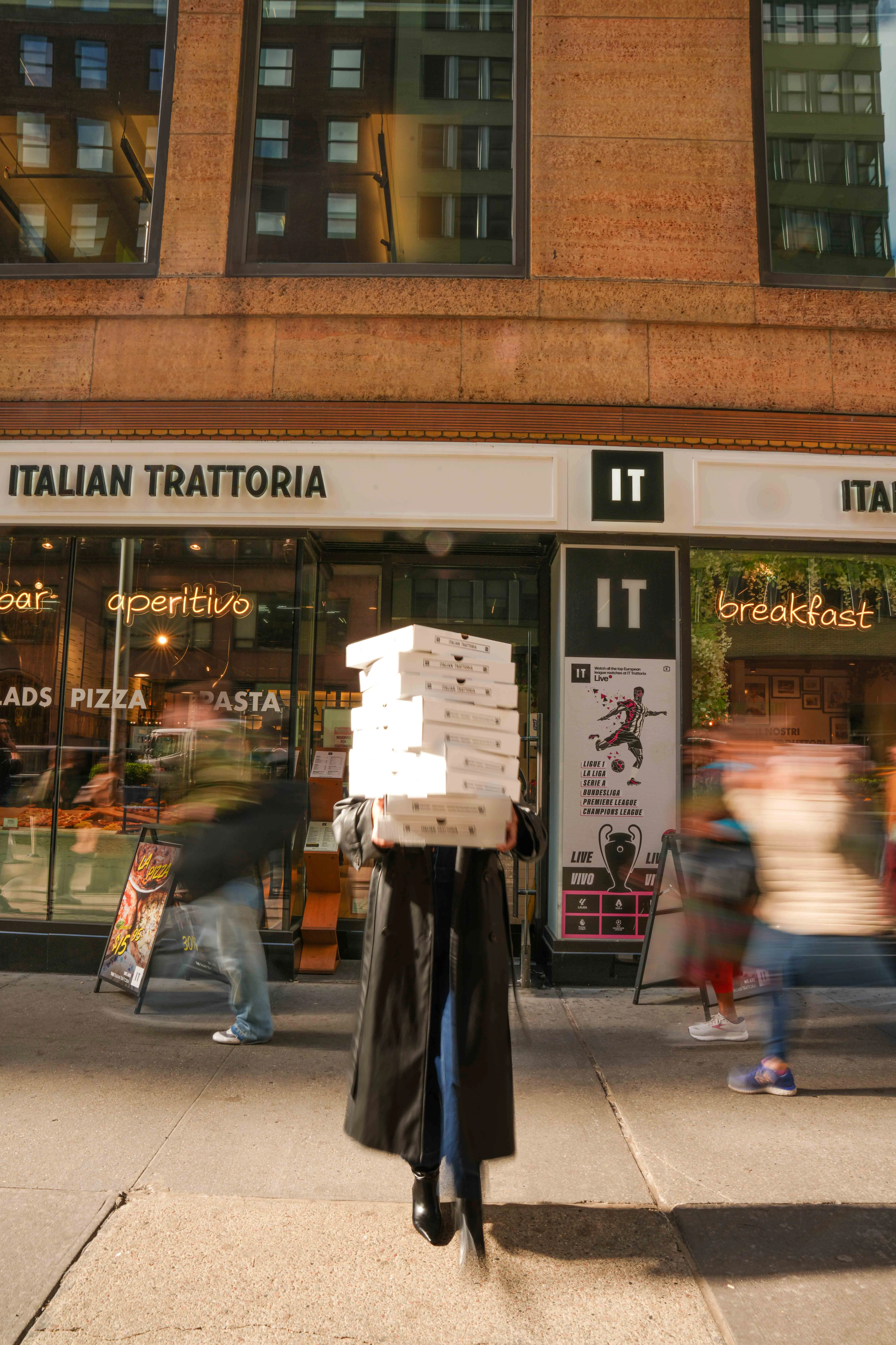 Delivery of stacked pizza boxes outside an Italian trattoria