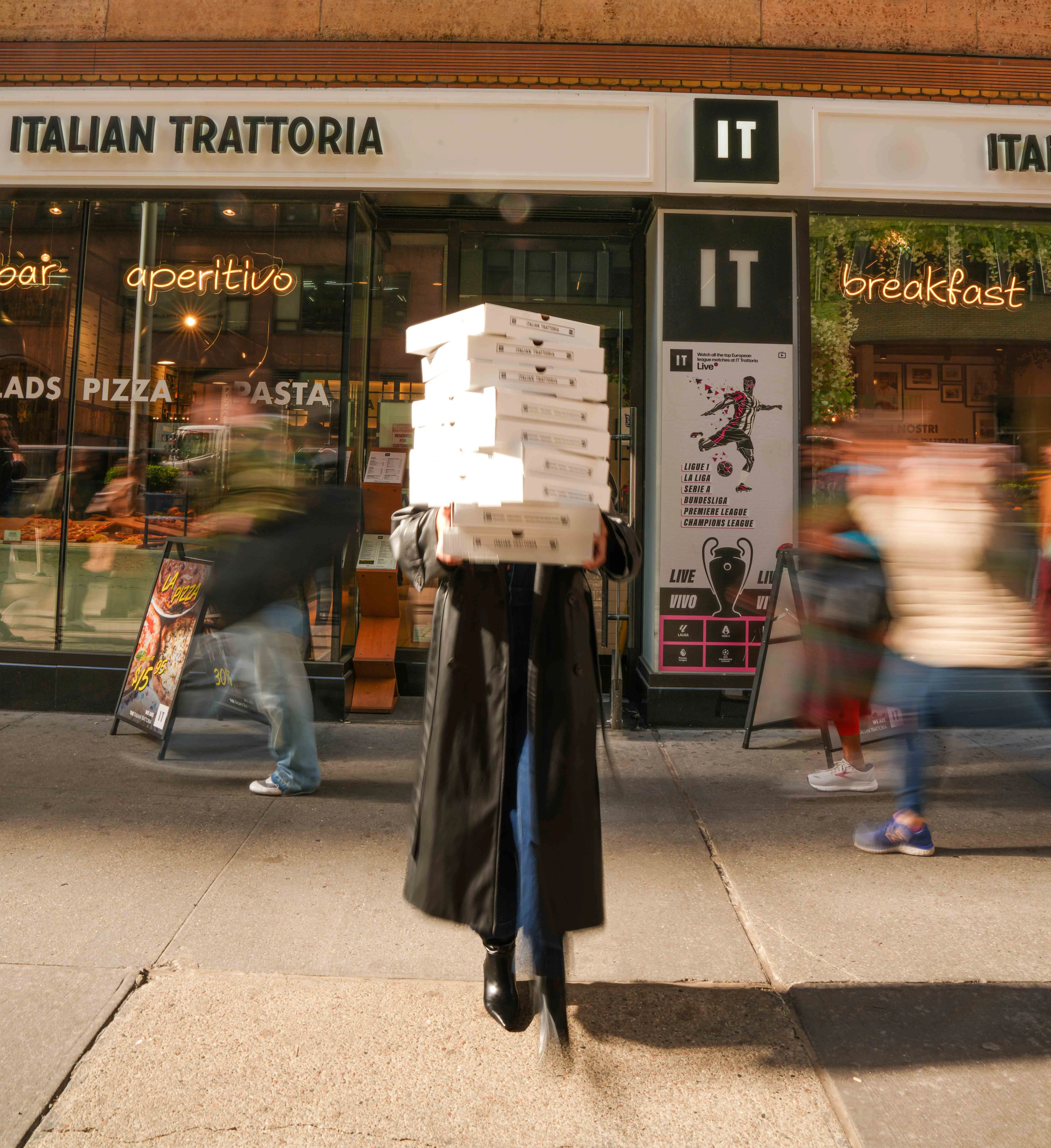 Delivery of stacked pizza boxes outside an Italian trattoria