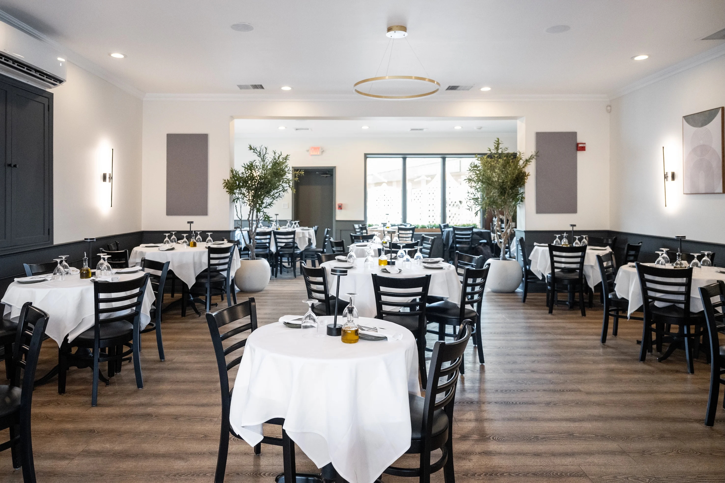 Elegant dining area with white tablecloths, black chairs, and modern decor, perfect for a fine dining experience at Toscana on Main Westchester.