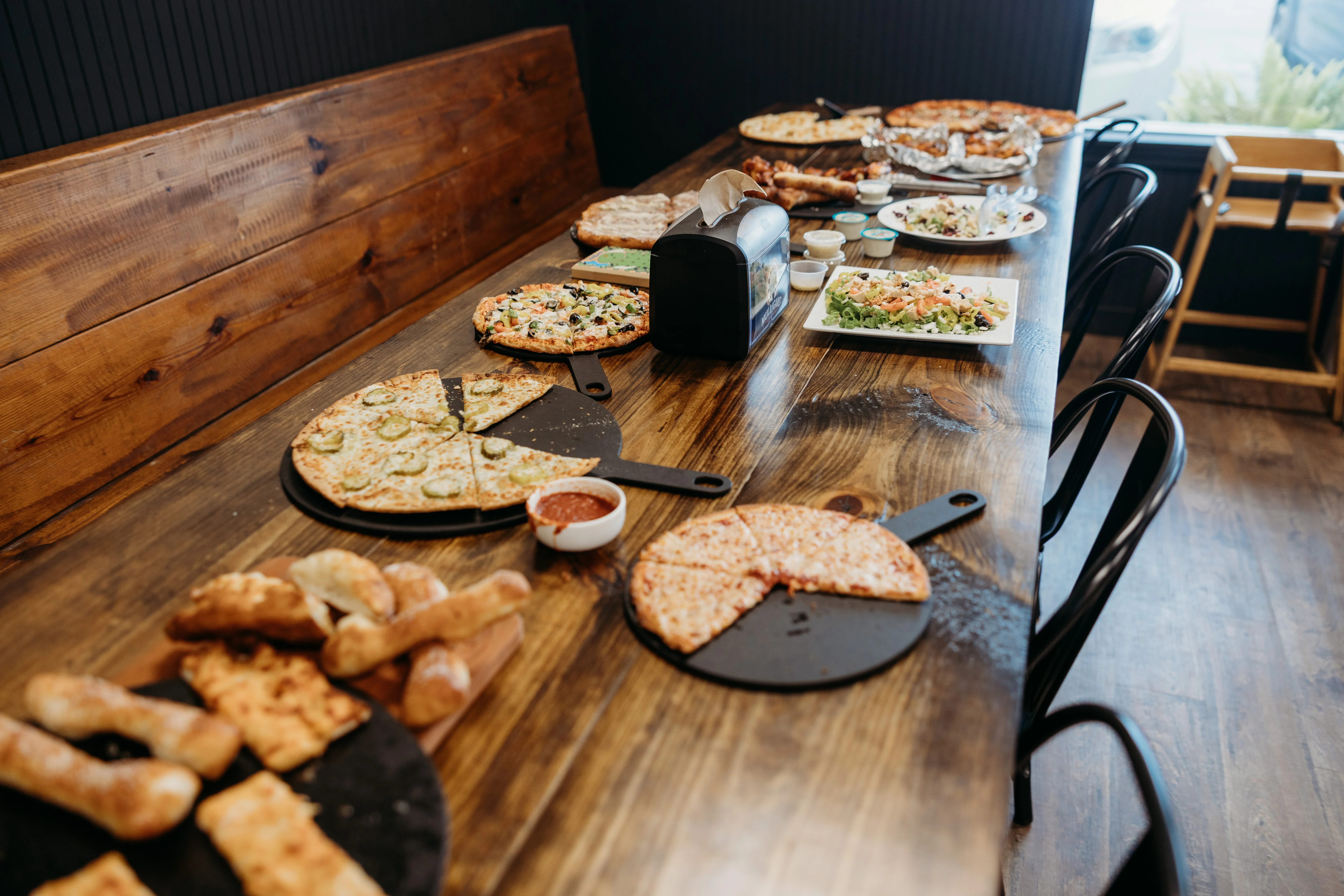 Variety of pizzas and salads on a rustic wooden table