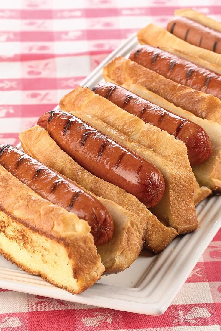 Grilled hot dogs in soft buns on a picnic table