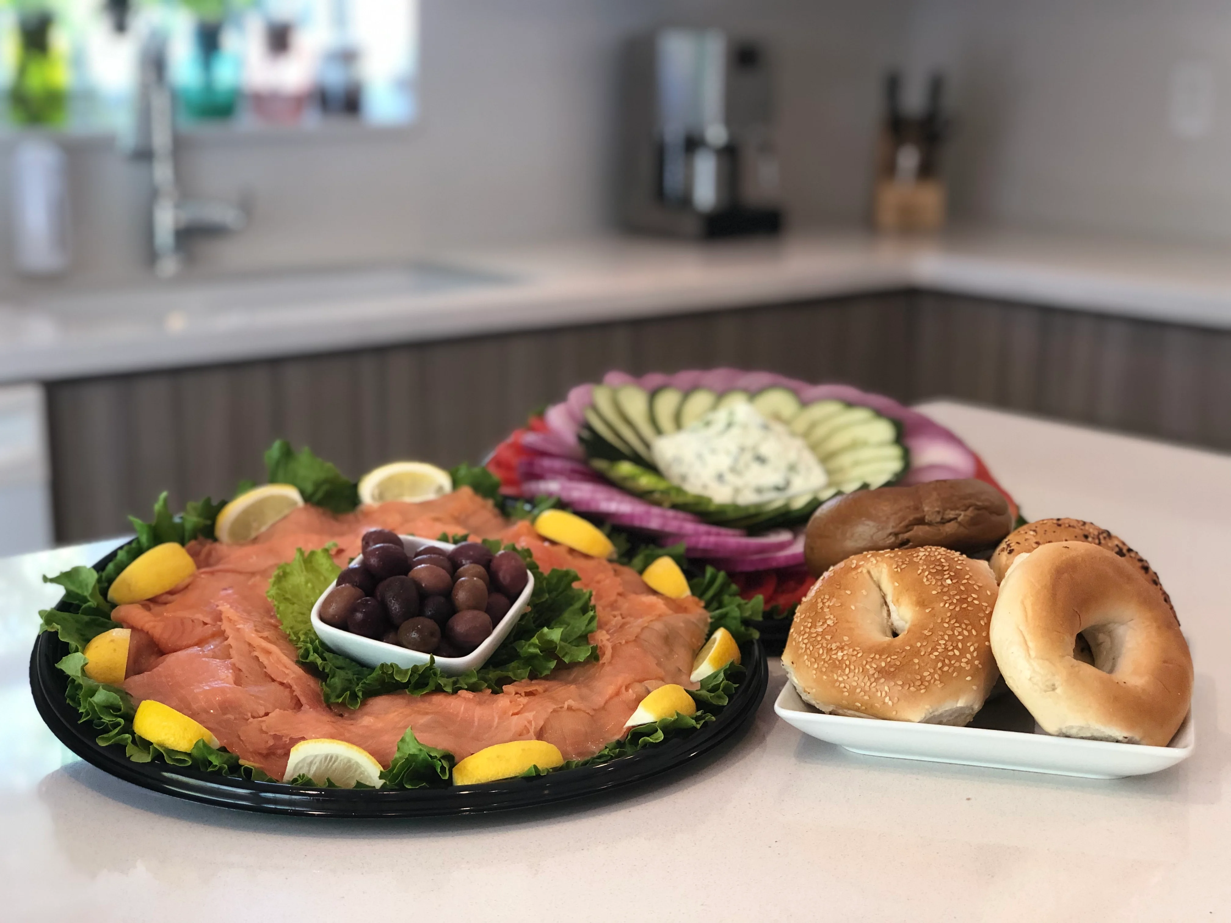 Home catering spread with nova platter, bagels, vegetables, and deli sides