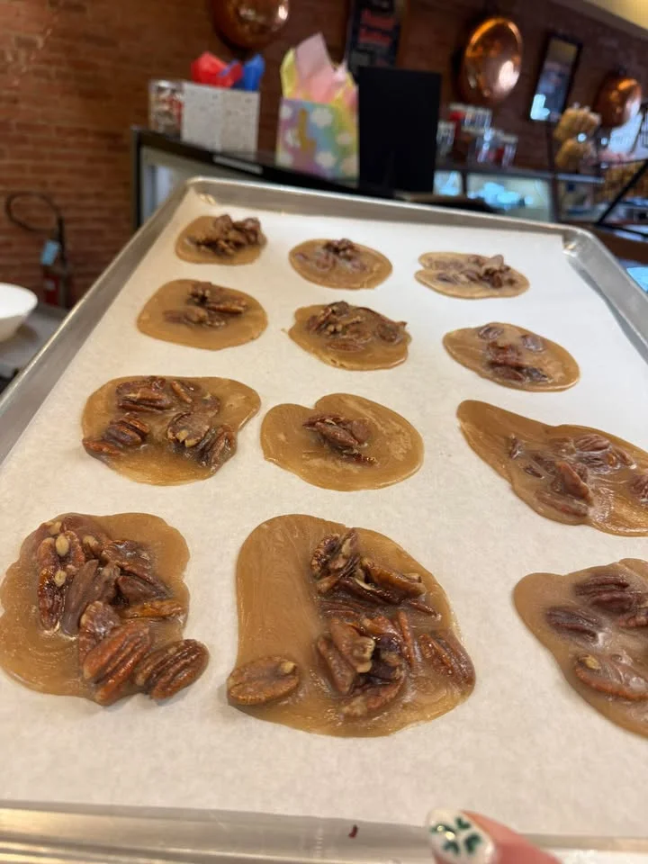 A baking sheet lined with caramel candies featuring whole pecans embedded within the sweet mixture.