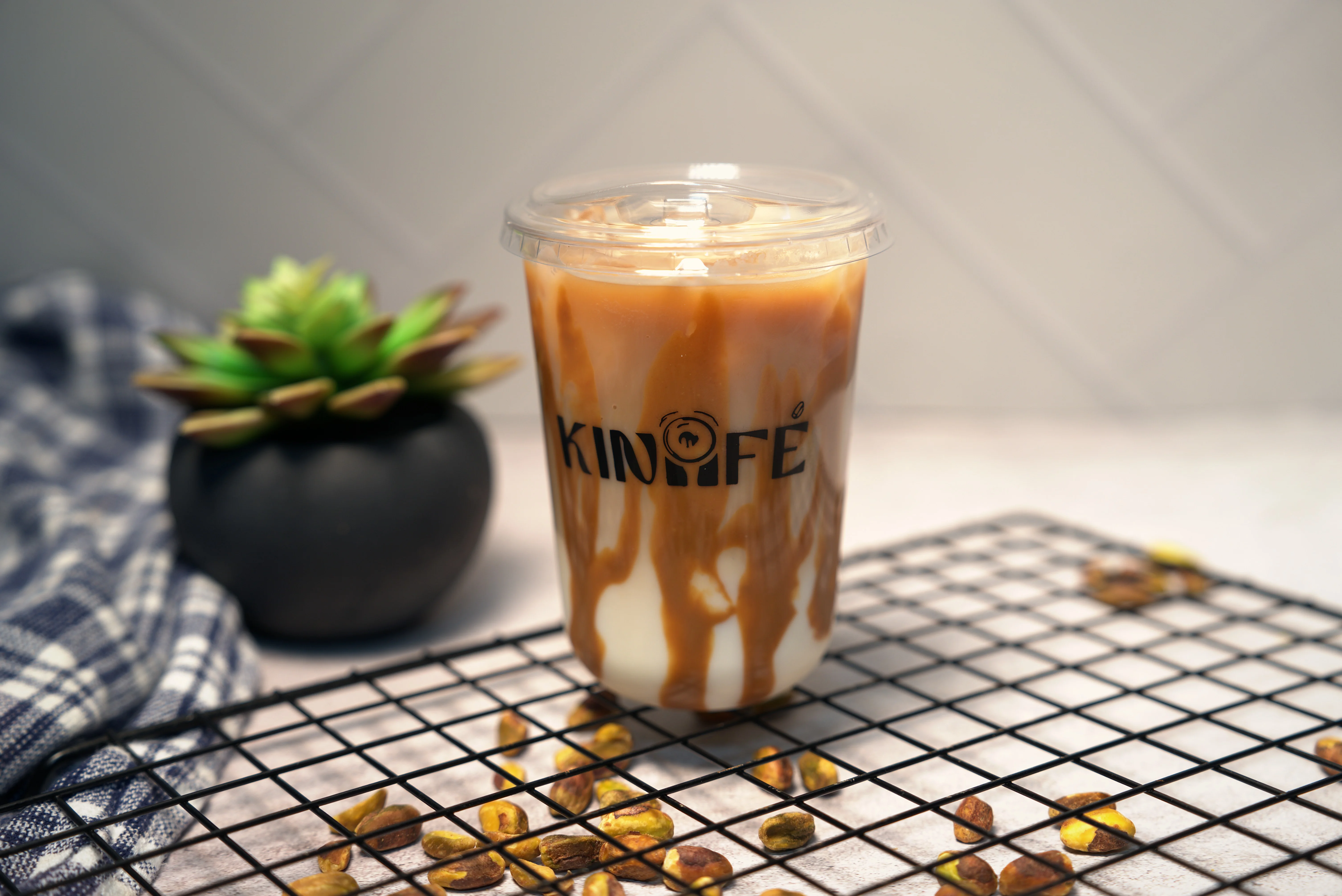 A cup of iced coffee featuring a swirled design topped with a clear lid, set against a neutral background.