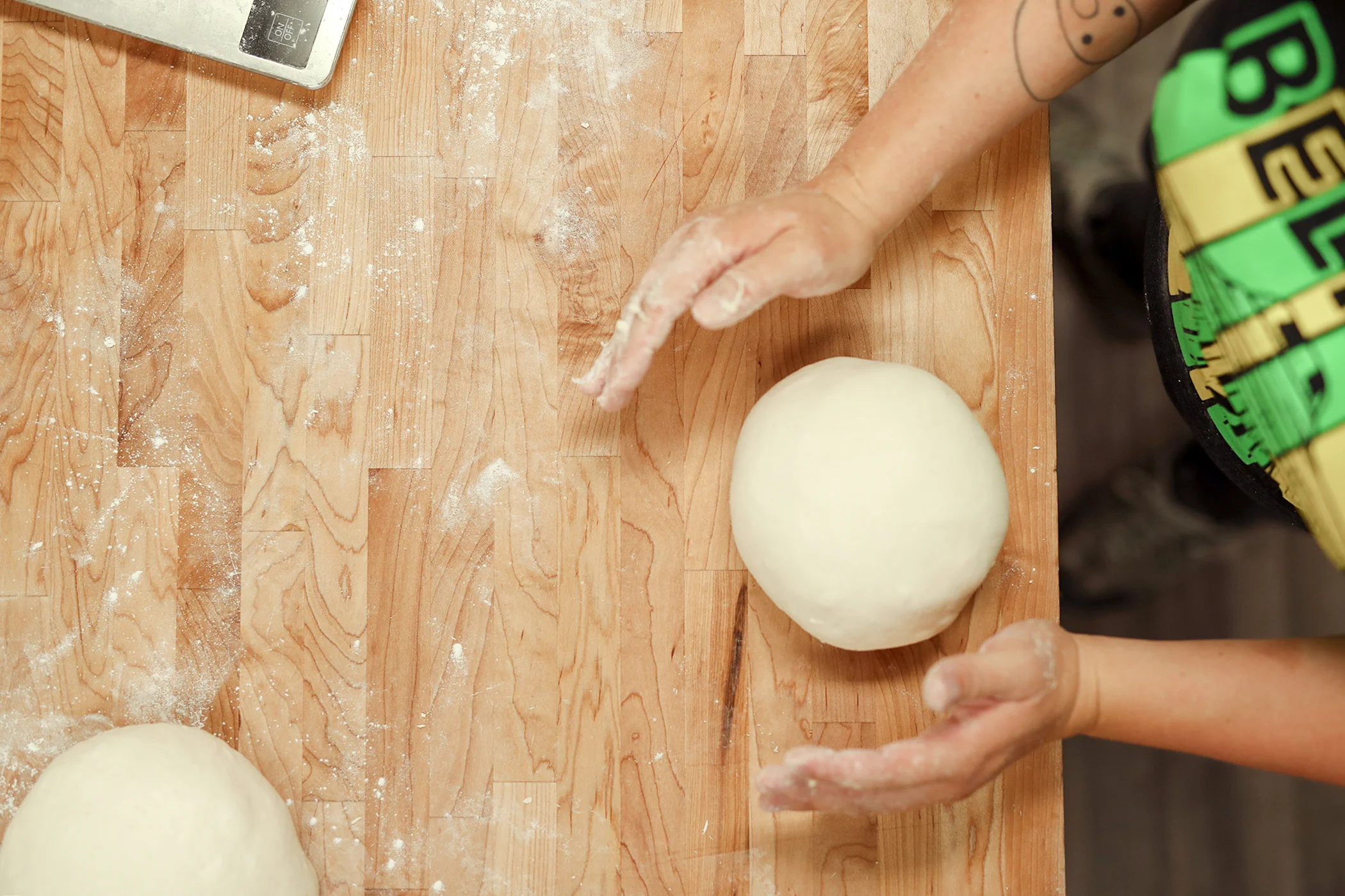 Baker shaping dough balls on a wooden countertop