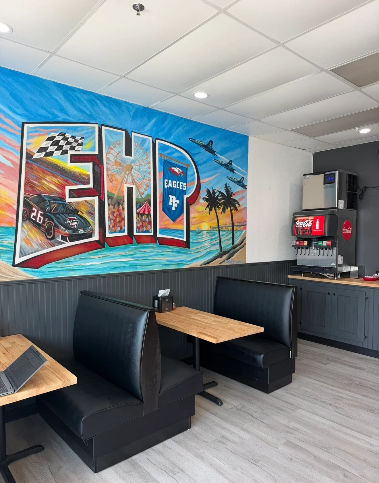 Bright restaurant dining area with colorful sports mural and booth seating