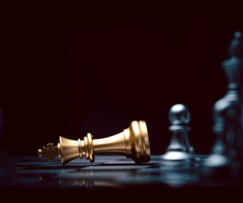 Fallen golden king chess piece on a dark board