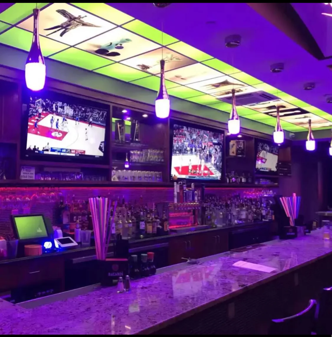 Modern bar interior with vibrant lighting and multiple TVs