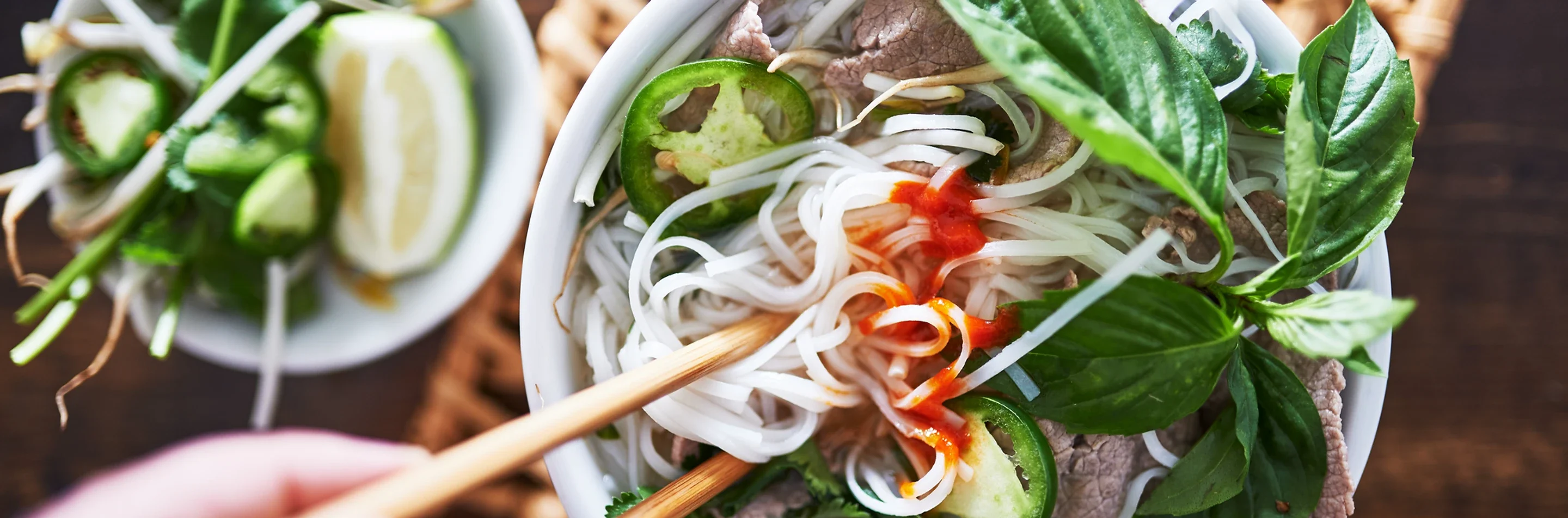 Bowl of Vietnamese pho with fresh herbs and beef