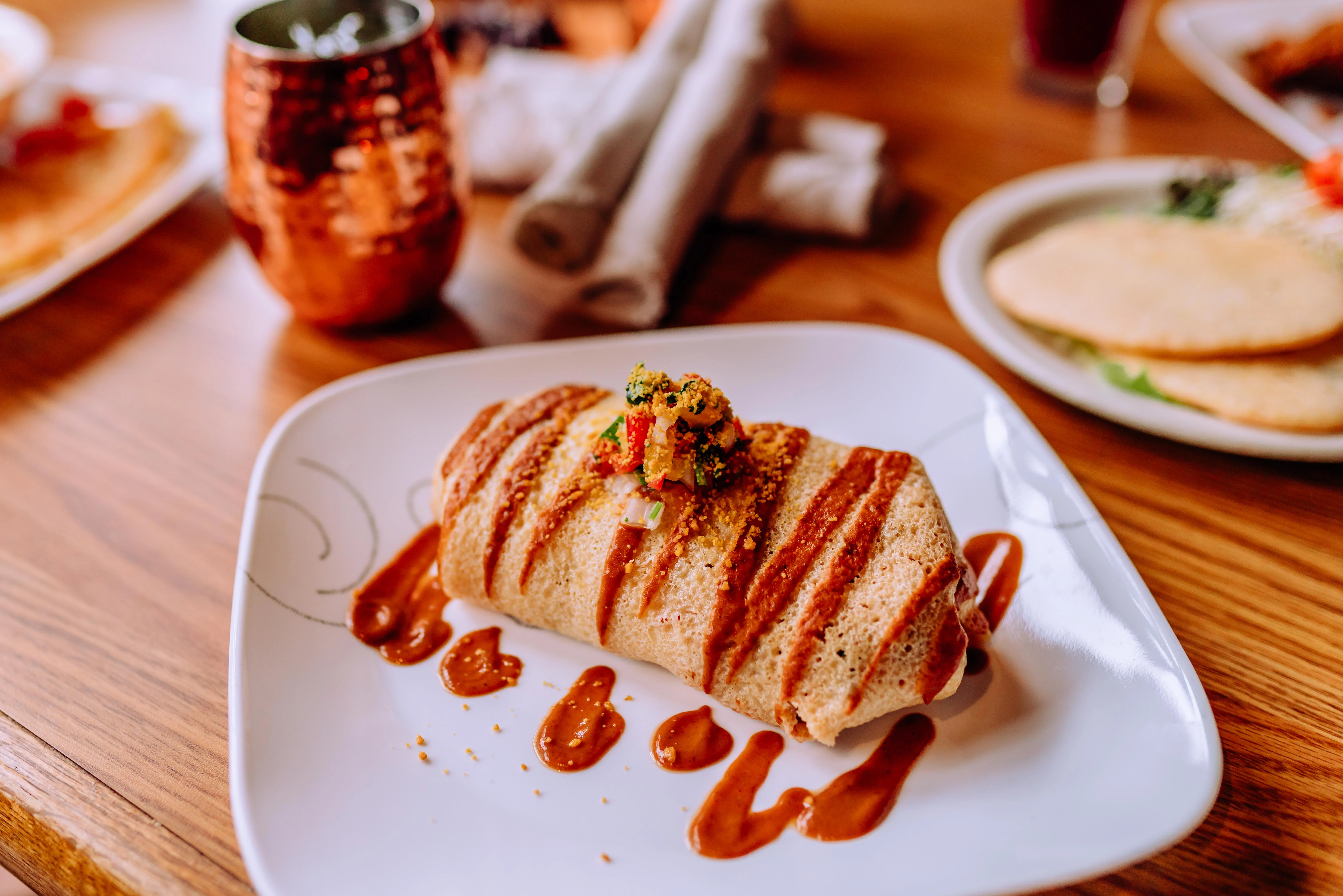 Delicious Mexican burrito drizzled with sauce and topped with fresh salsa