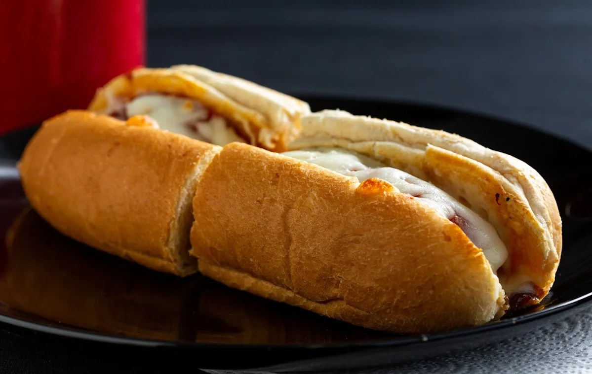 Cheesy Italian sausage sub sandwich on a black plate