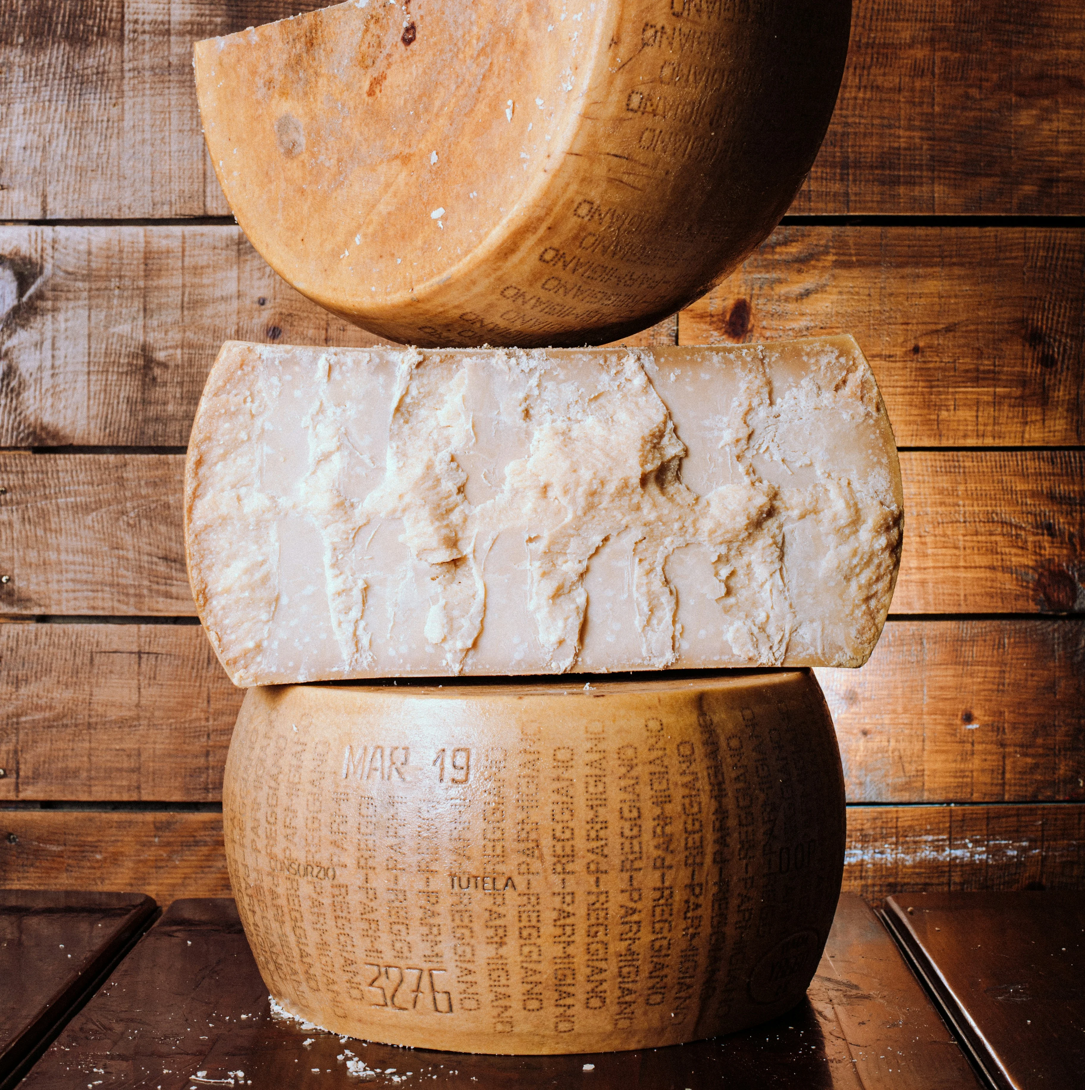 Parmigiano Reggiano cheese wheel with wedges on a rustic wooden table